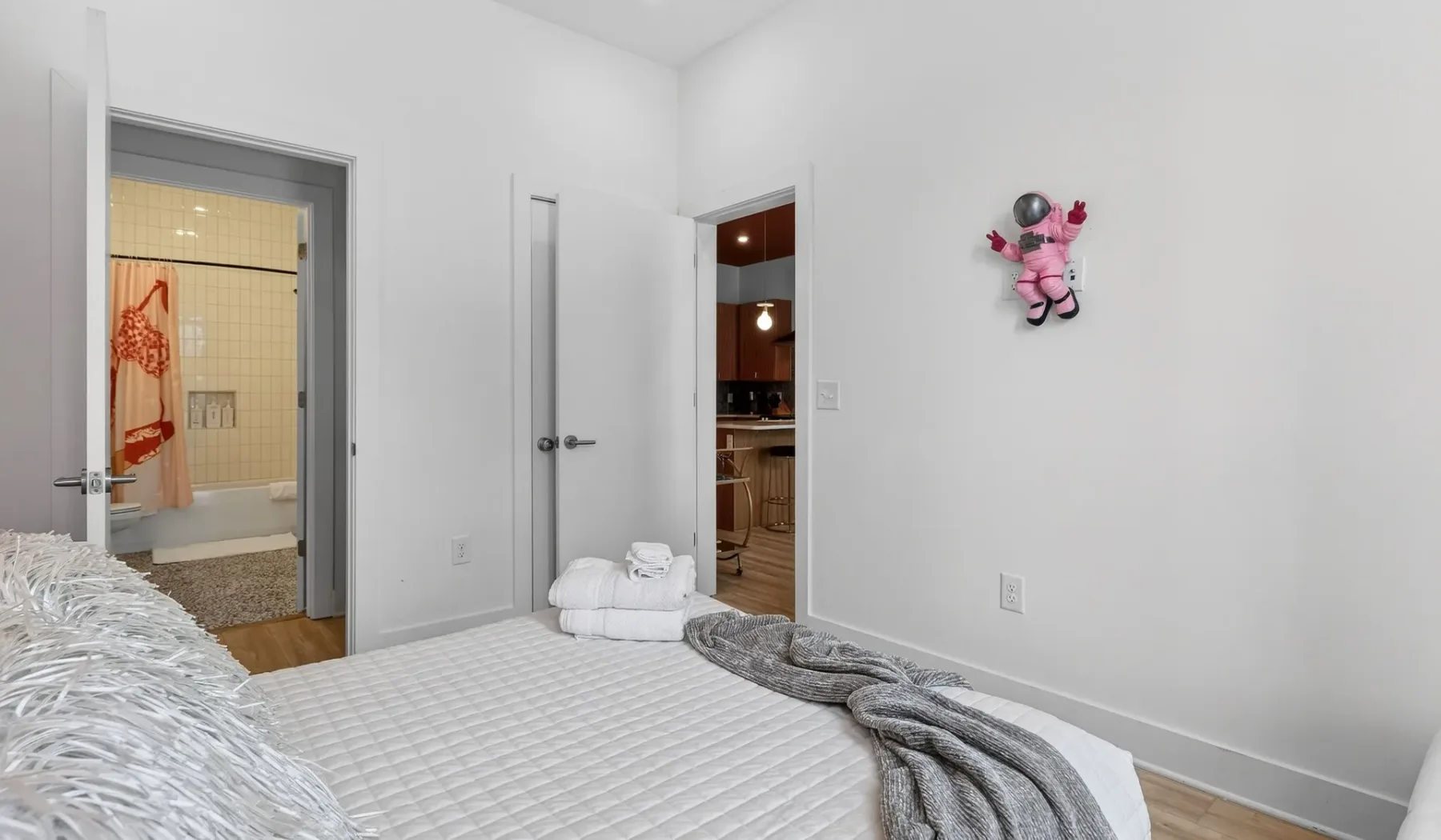 A bedroom with a neatly made bed and an open doorway to the bathroom.