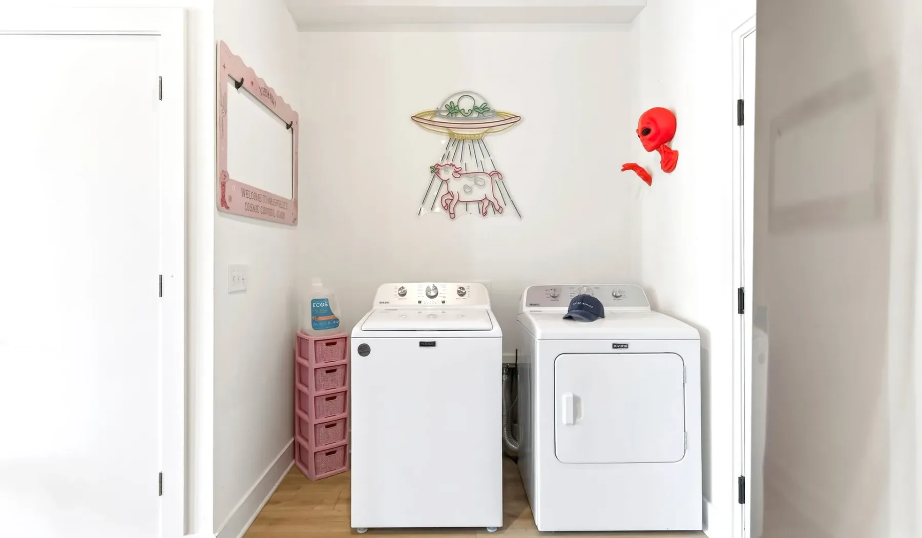 A laundry area with a washing machine and dryer beneath playful wall decorations.