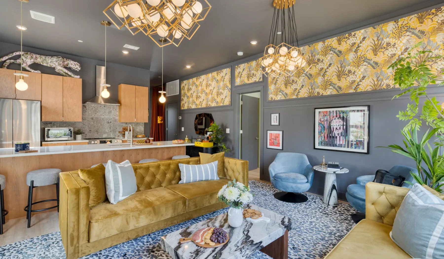 A living room with gold seating, patterned wall panels, and pendant lights.