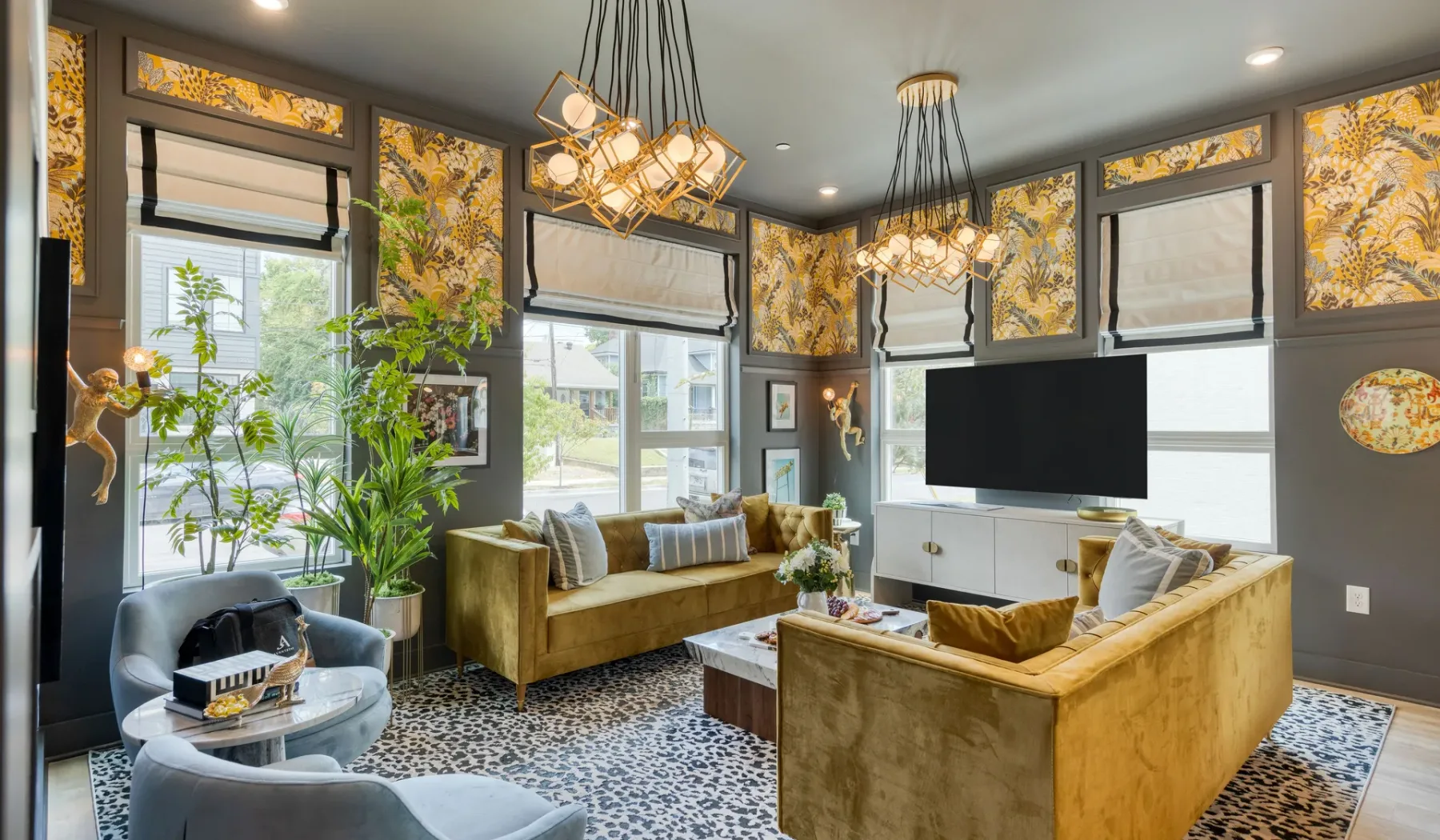 A living room with seating, a wall-mounted television, and tall windows.