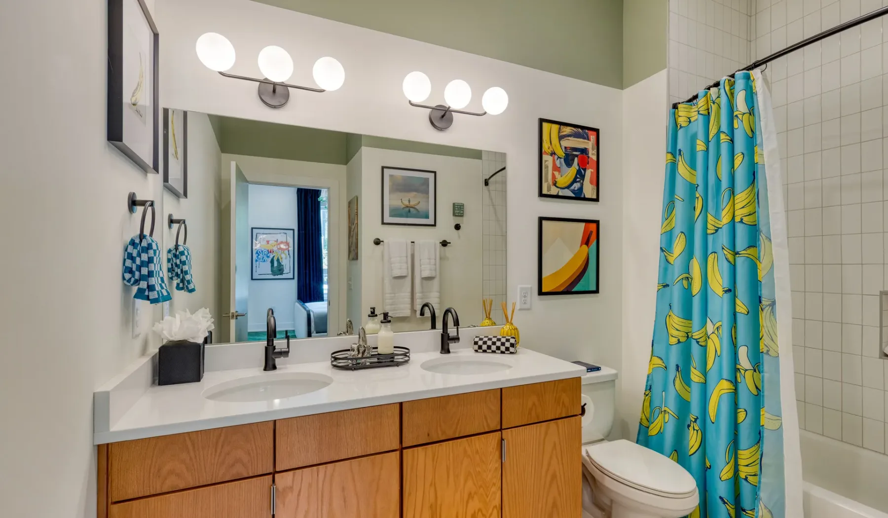 A bathroom vanity with a broad mirror and a colorful shower curtain.