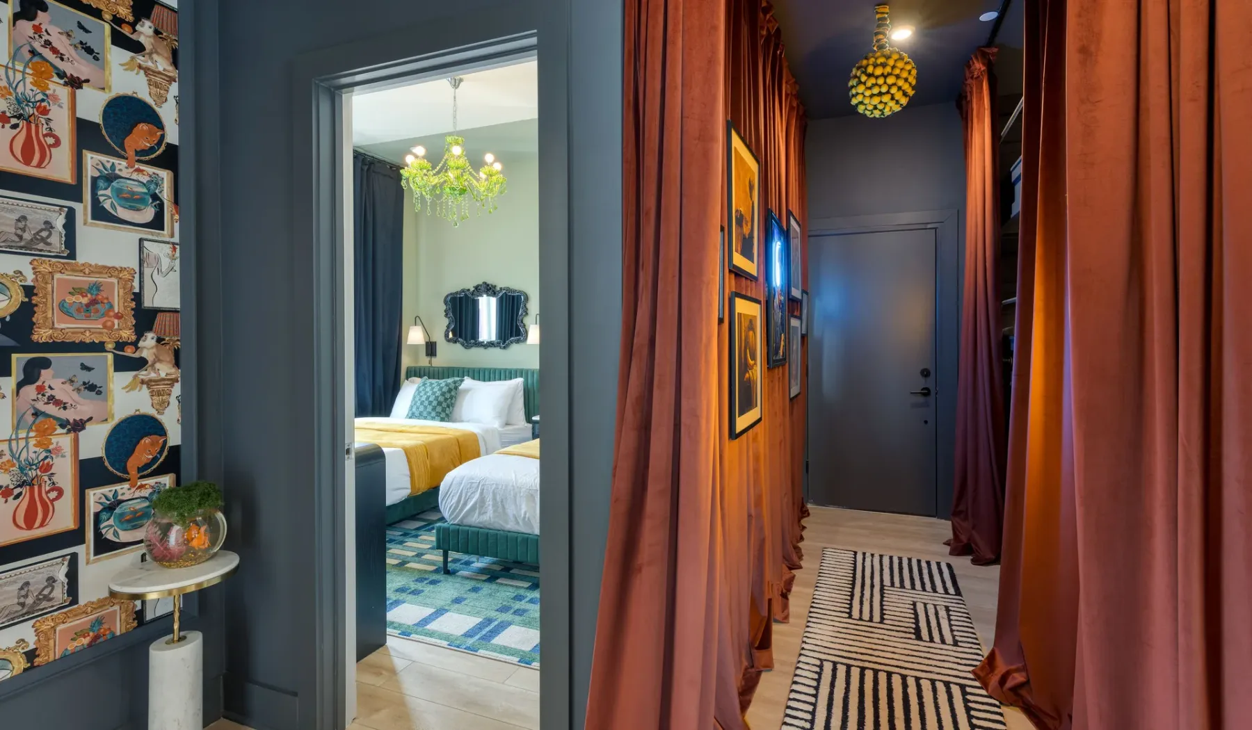 A curtained hallway with framed artwork and a patterned runner leads to a bedroom.