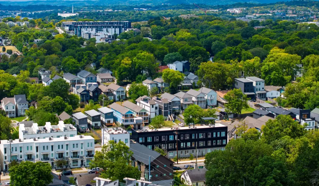 Aerial view of a wooded residential neighborhood with homes and apartment buildings.