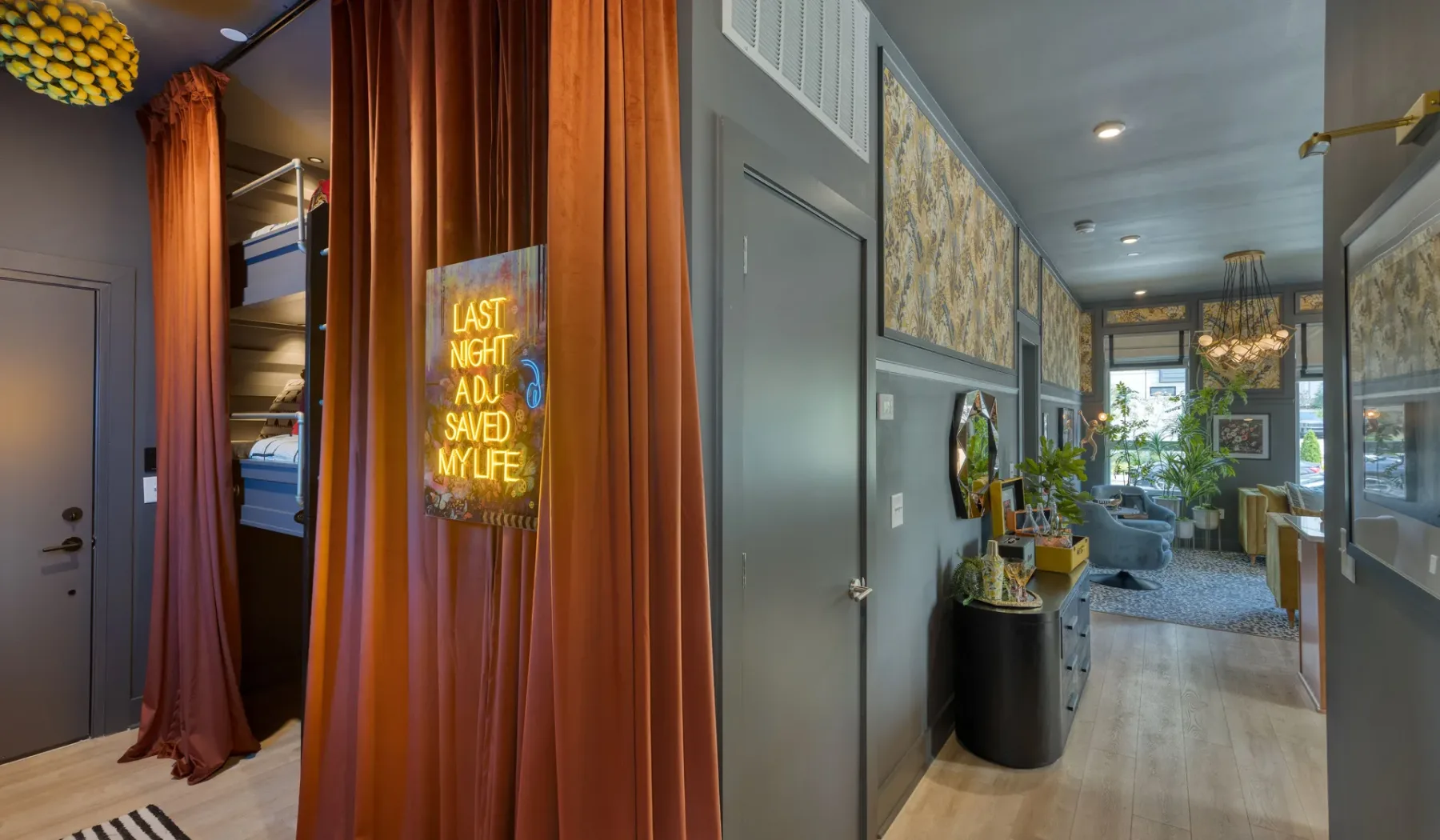 A hallway opens toward a living area, with a curtained sleeping nook along the side.