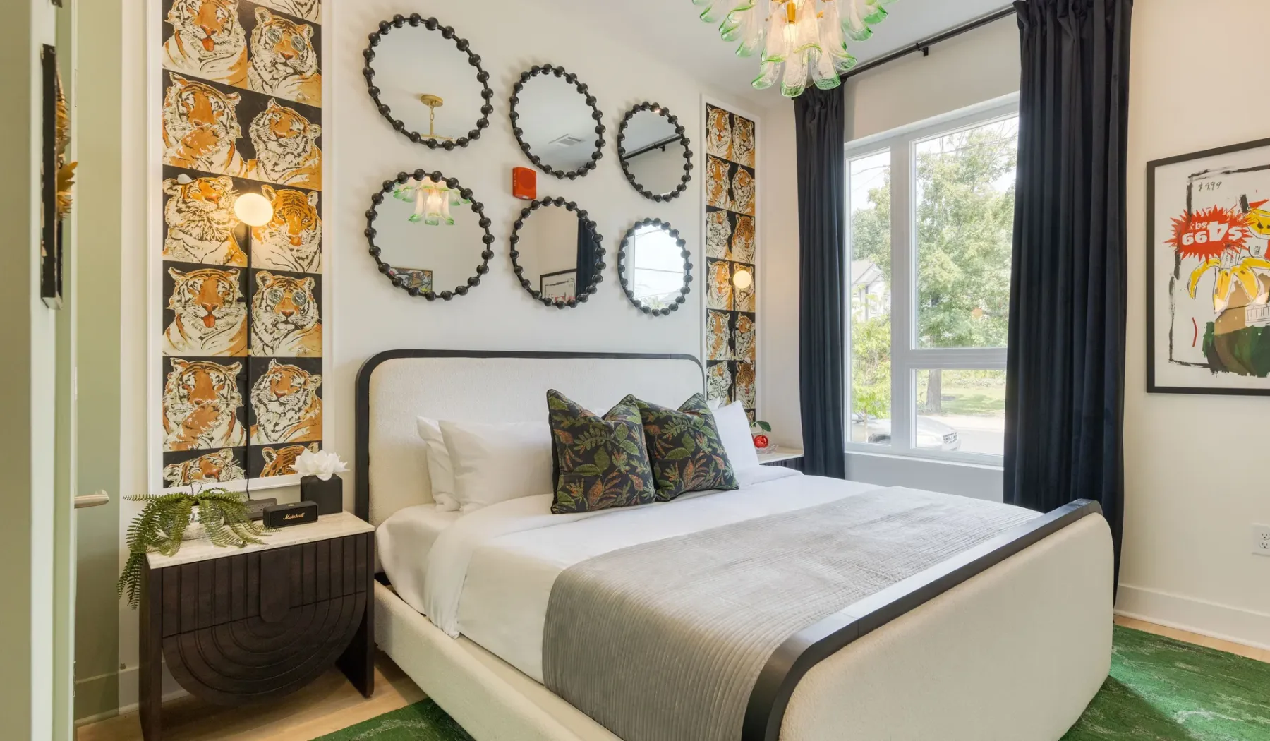 Dormitorio con una cama bien arreglada, espejos decorativos y una ventana grande.