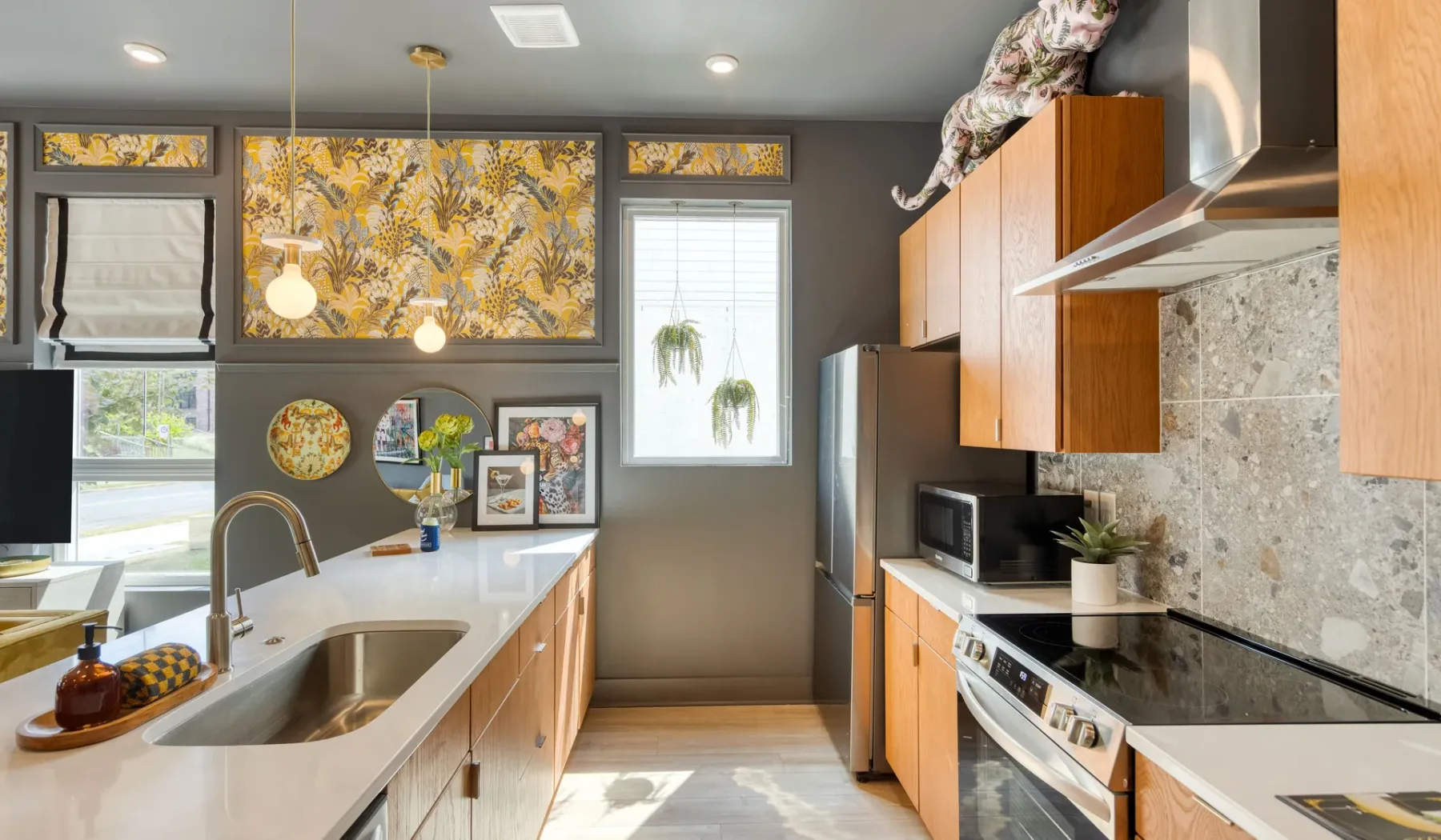 A bright kitchen with wooden cabinets, a long counter, and stainless steel appliances.