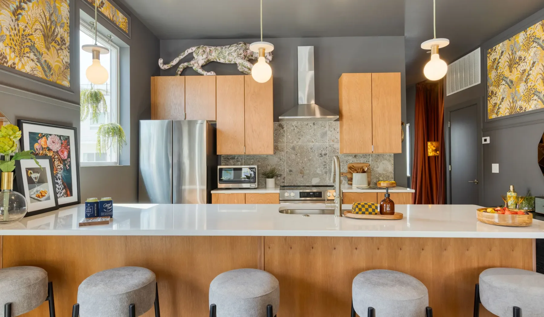 Una cocina moderna con una amplia barra, taburetes y electrodomésticos de acero inoxidable.