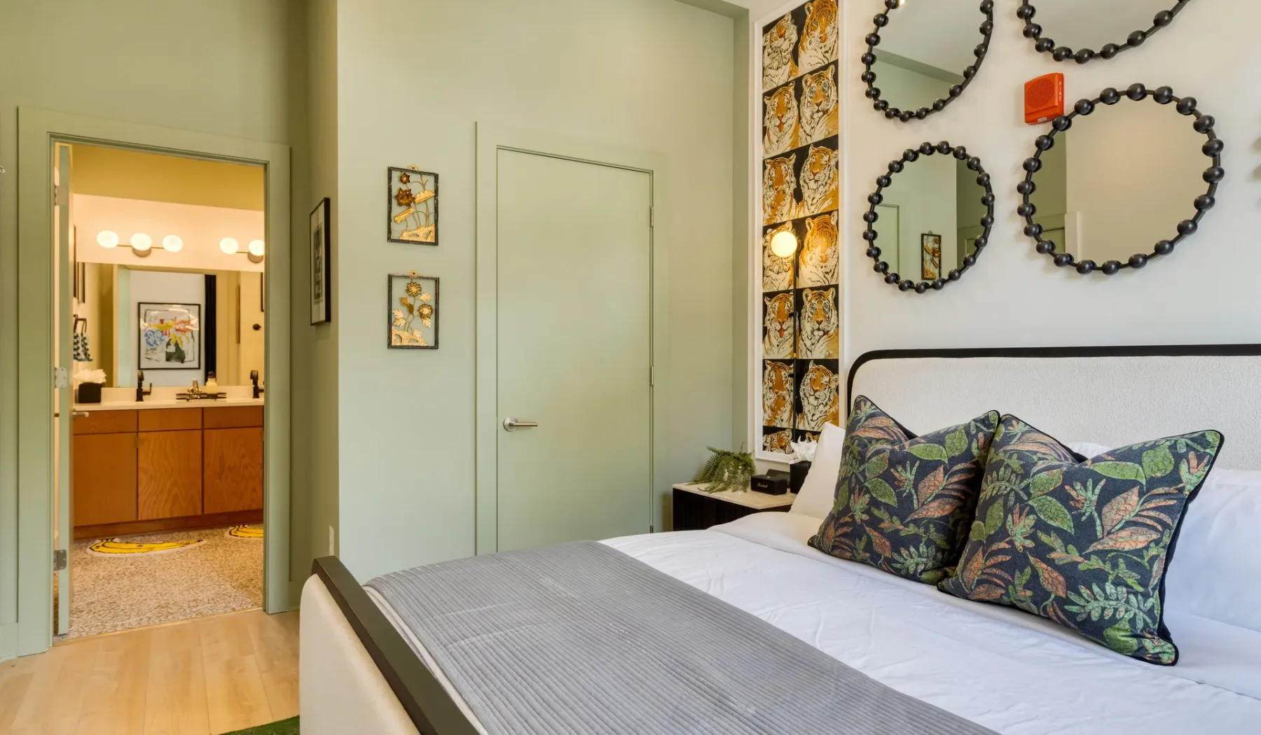 A bedroom with a neatly made bed and patterned pillows.