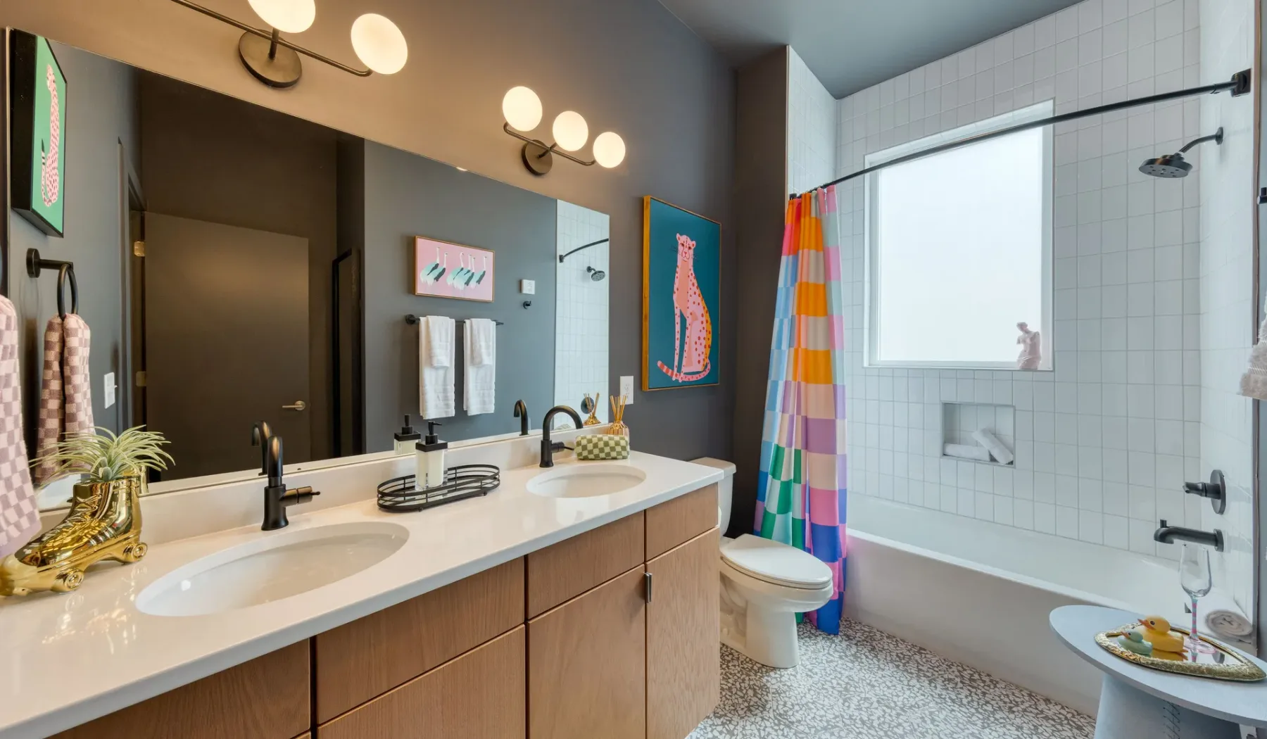 A bright bathroom with a double-sink vanity and a bathtub.
