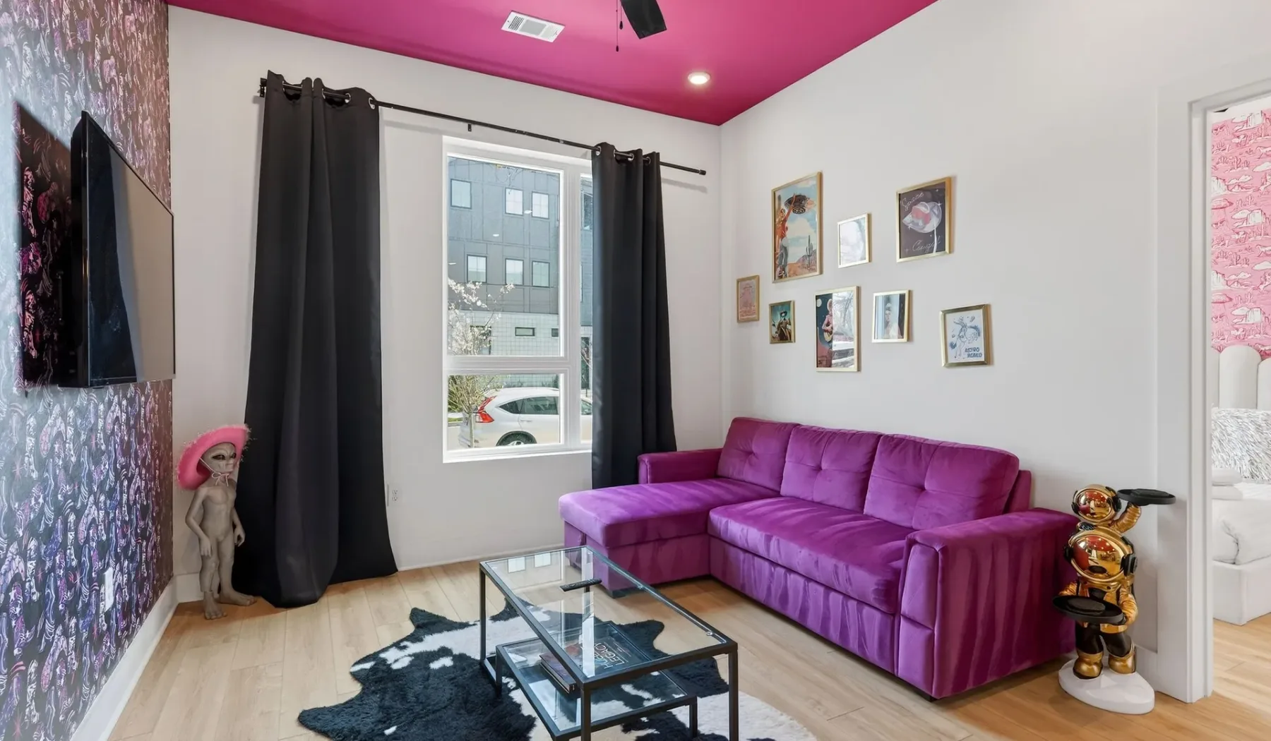 A living room with a purple sofa, dark curtains, and a glass coffee table.