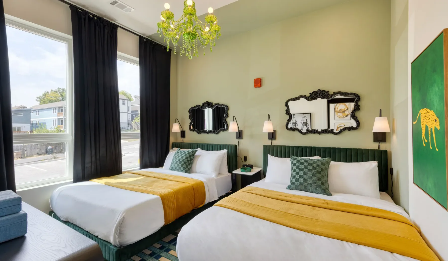A bright bedroom with two beds, green headboards, and mustard-yellow bed runners.
