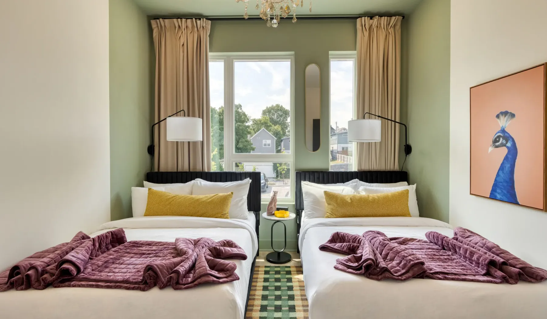 A bedroom with two beds, patterned blankets, and tall windows.