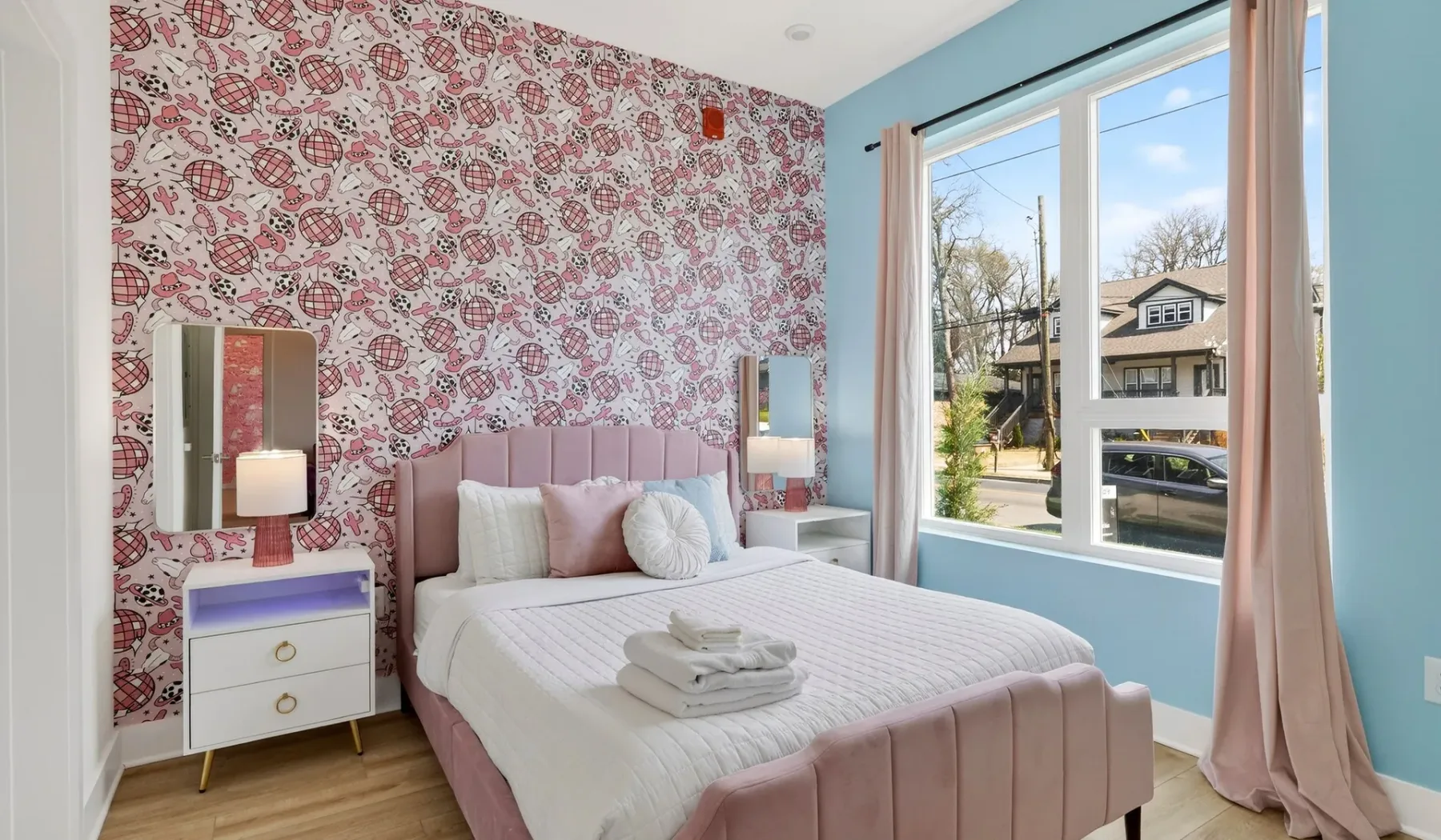 A bedroom with a pink bed and a large window.