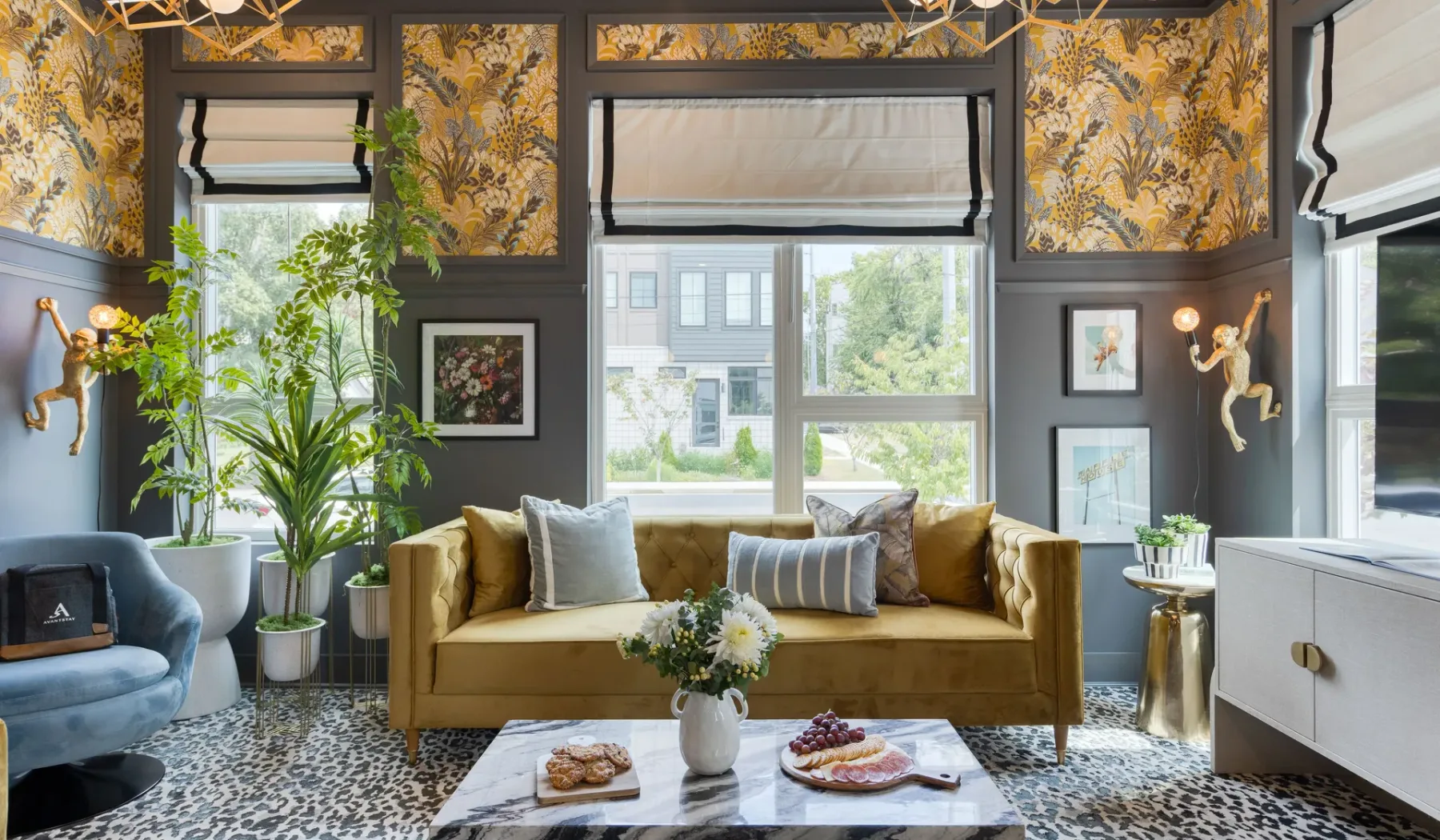 A living room with a mustard-colored sofa, patterned rug, and large windows.