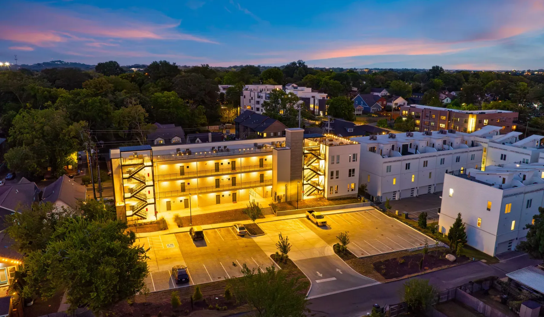 Aerial view of modern buildings and a parking area at dusk.