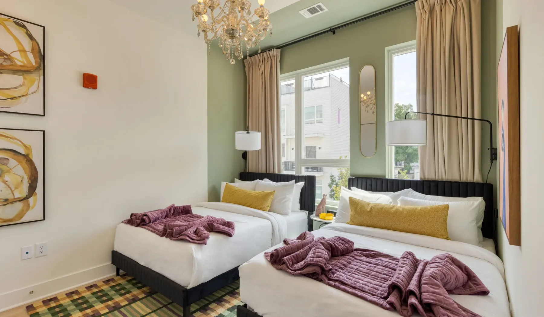 A bedroom with two beds, tall windows, and green walls.
