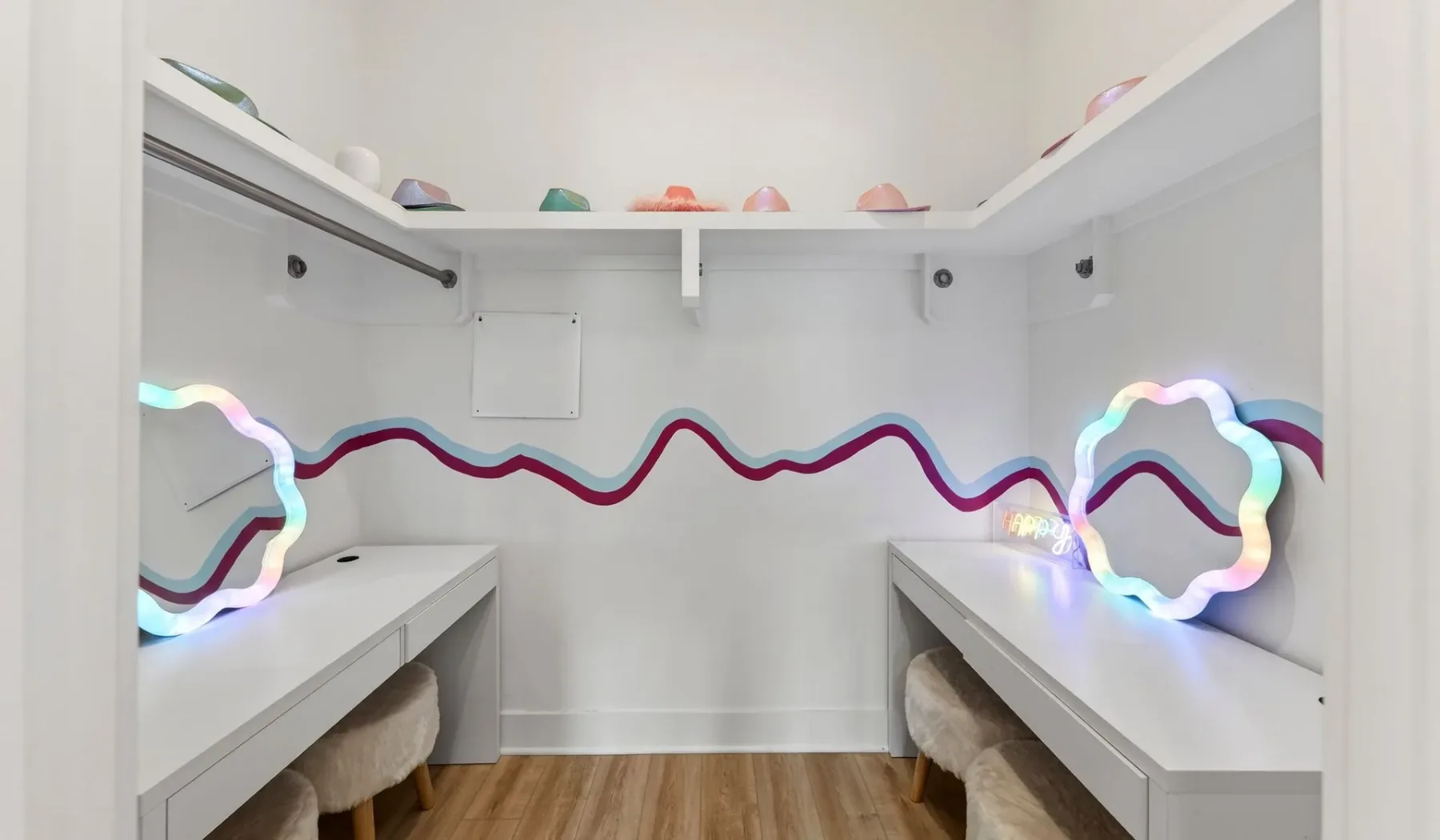 A bright dressing room with long counters and colorful wavy wall trim.