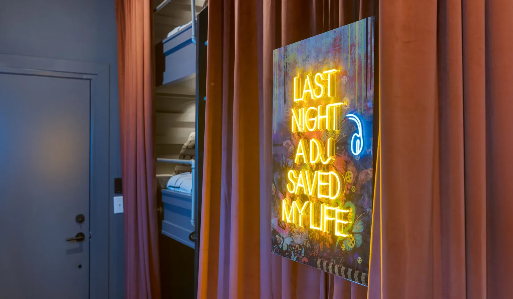 A curtained wall displays a colorful illuminated sign beside a doorway.