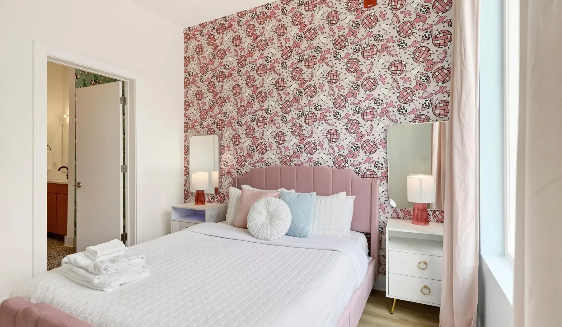 A bedroom with a pink headboard and patterned wallpaper.