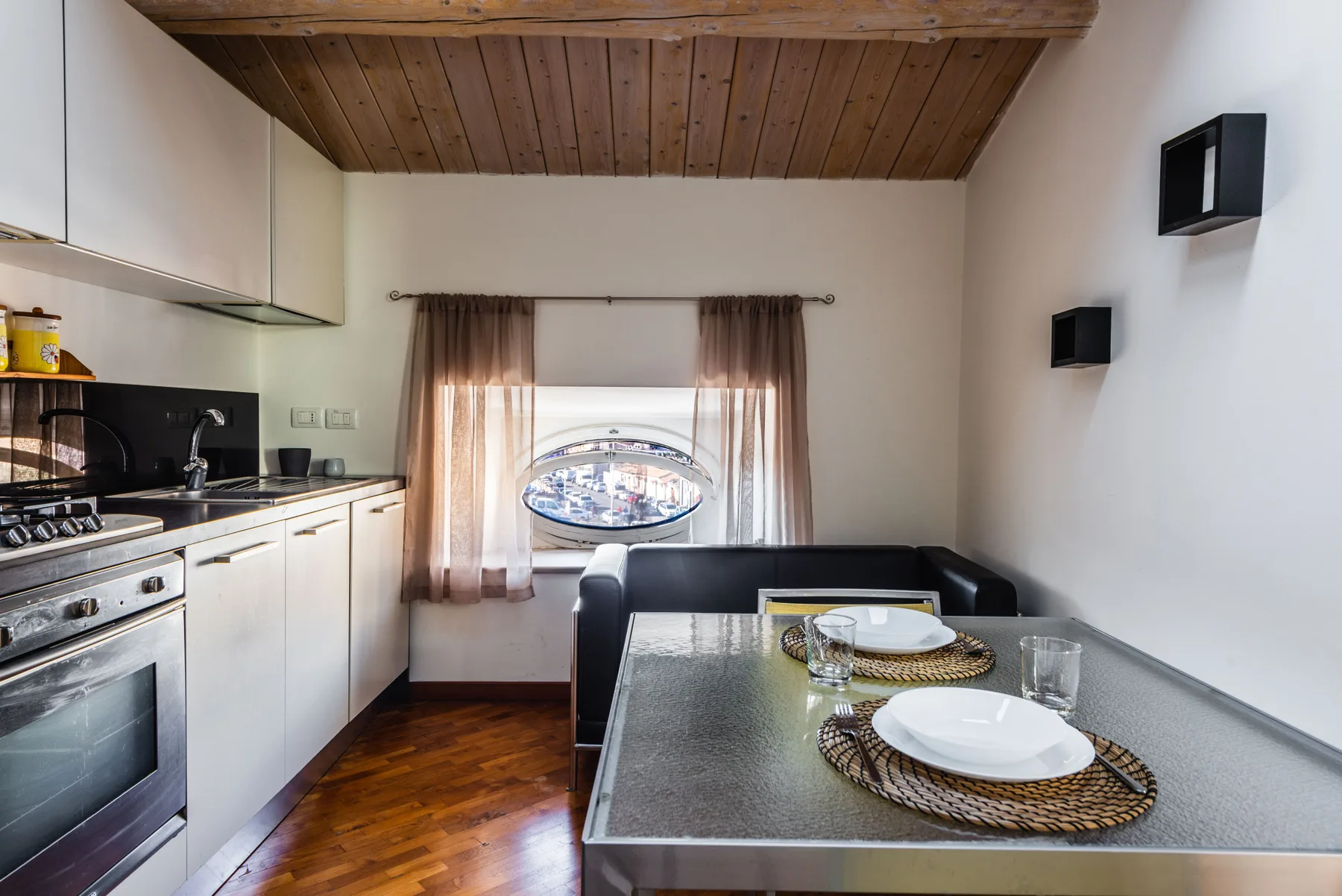 Una cocina compacta con zona de comedor y una mesa puesta junto a la ventana.