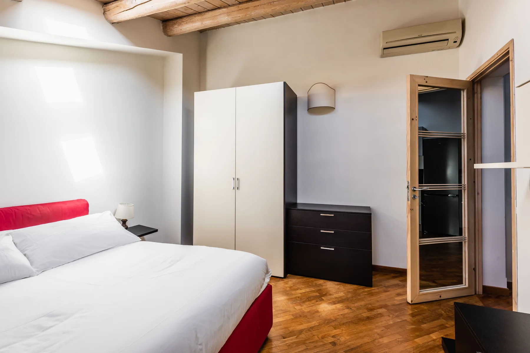 Un dormitorio con una cama, un armario y una cómoda oscura.