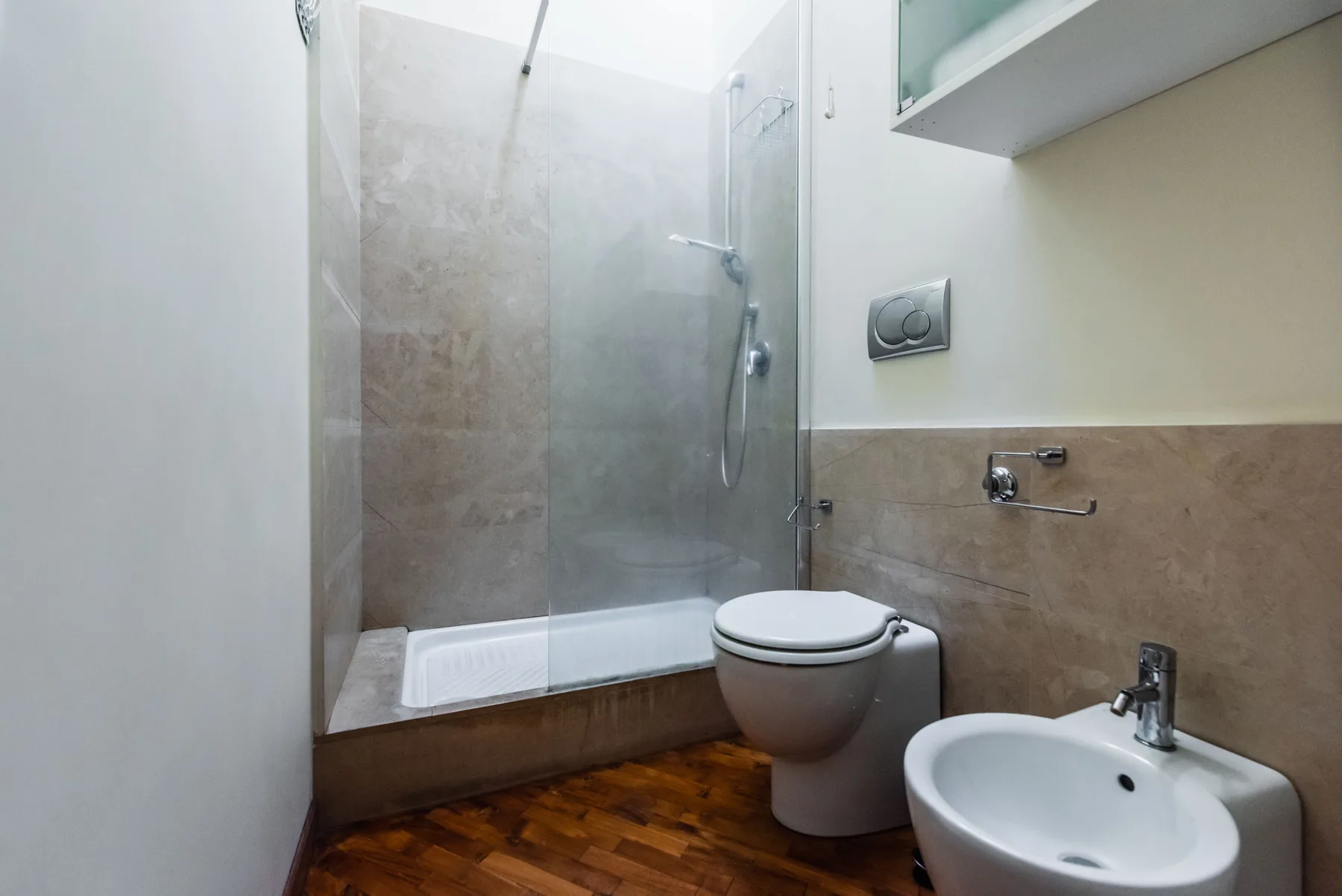 Un baño con ducha de cristal, inodoro y lavabo.