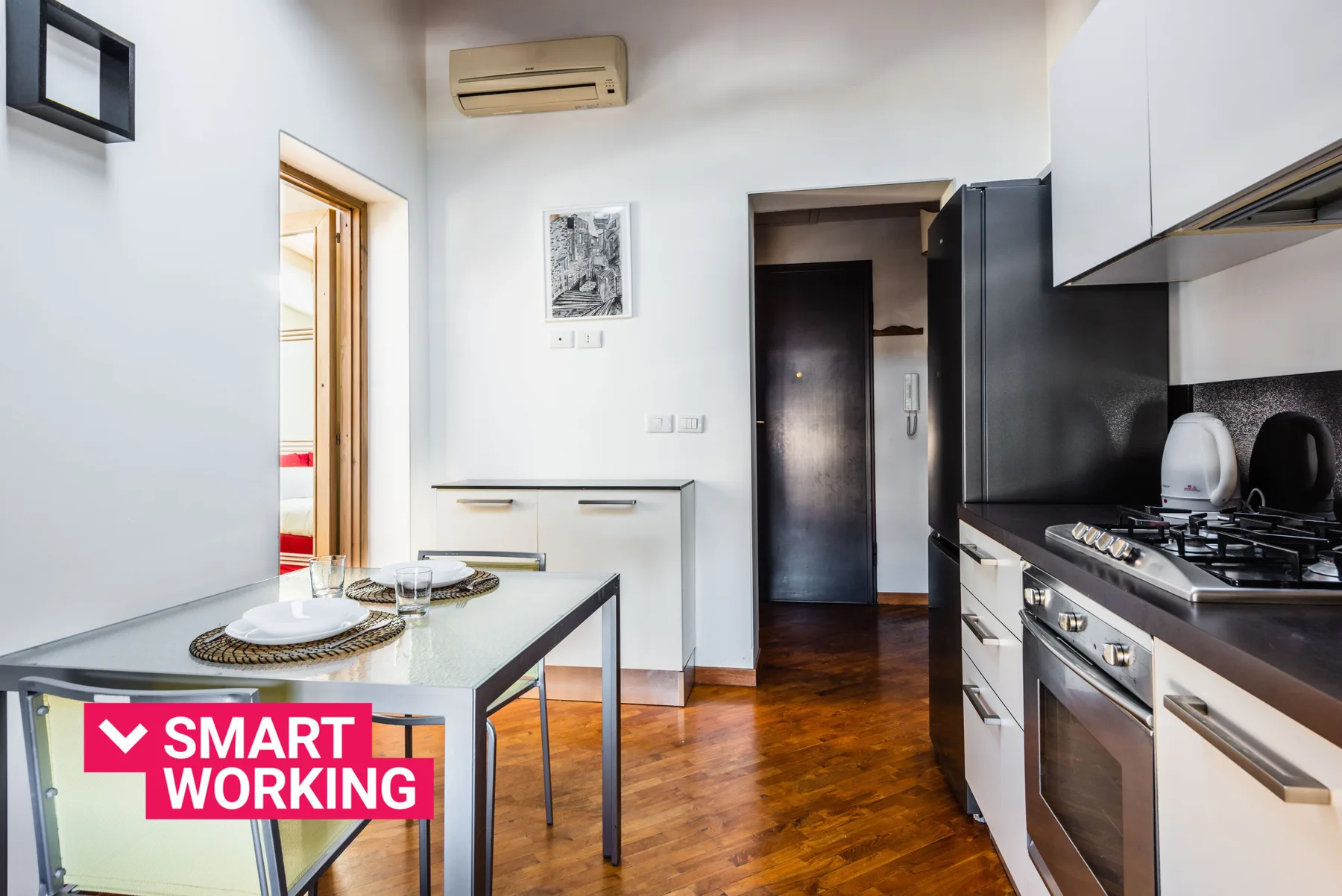 Una cocina con mesa, armarios y una cocina de gas.