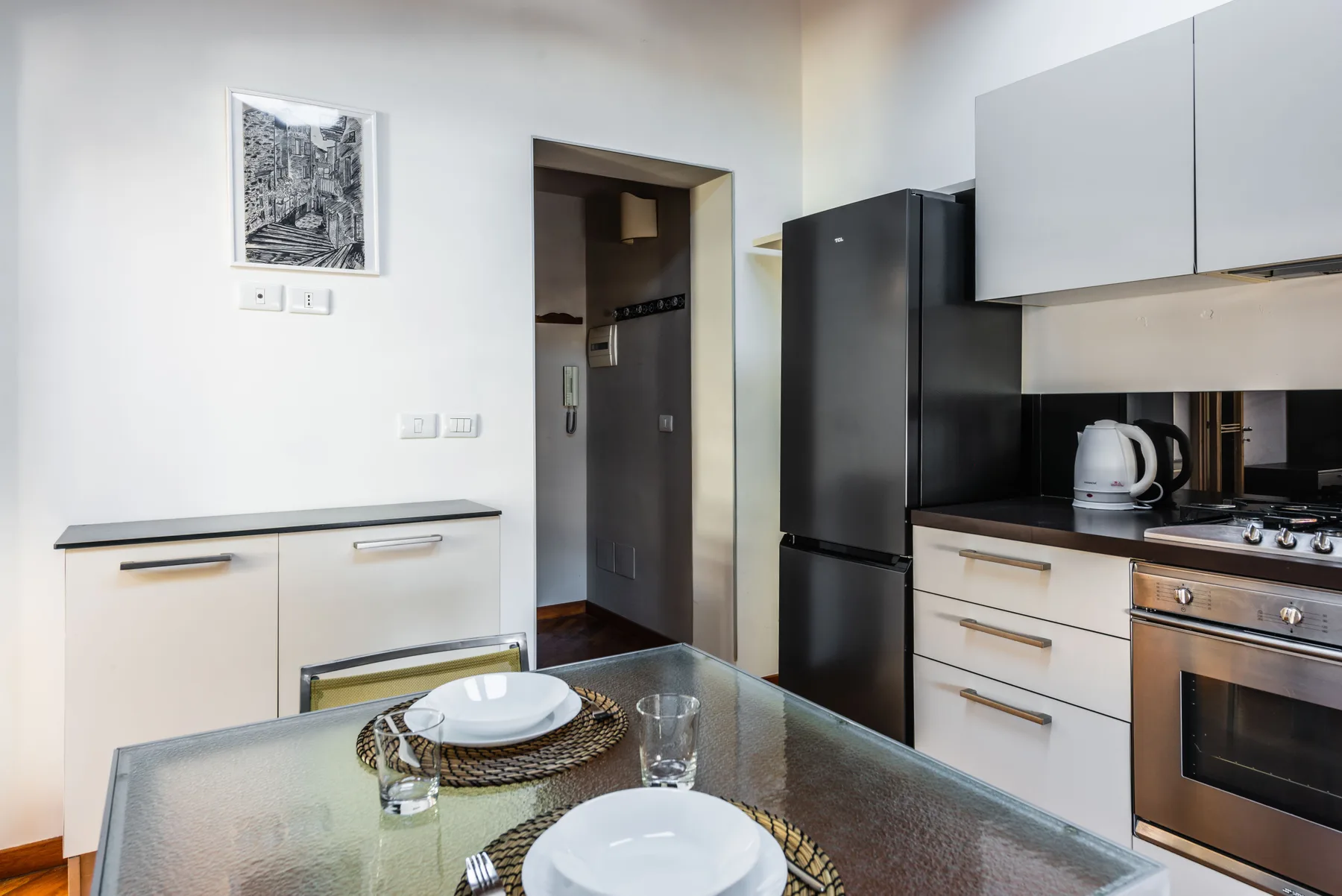 Una cocina compacta con refrigerador, gabinetes y una mesa de comedor.