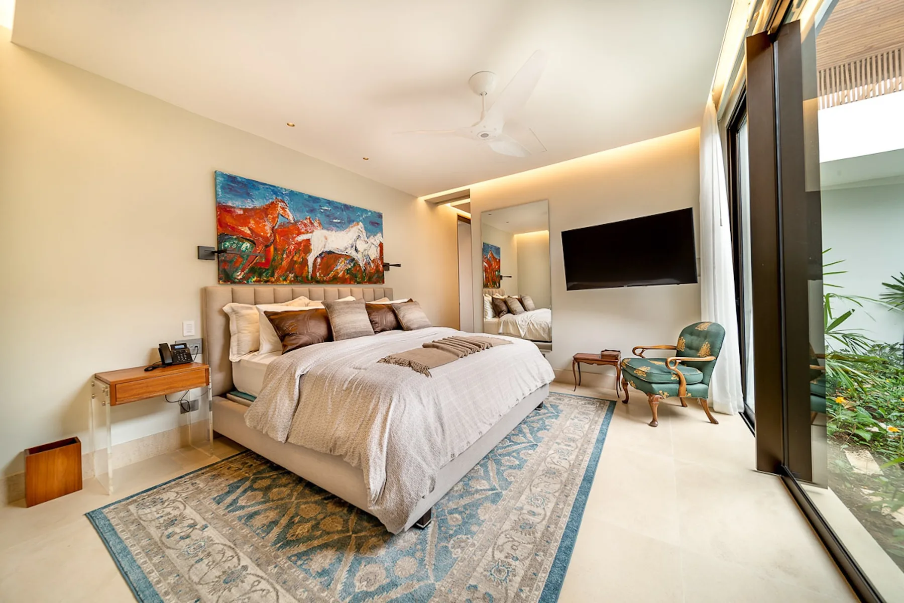 A bedroom with a large bed, colorful wall art, and a television.