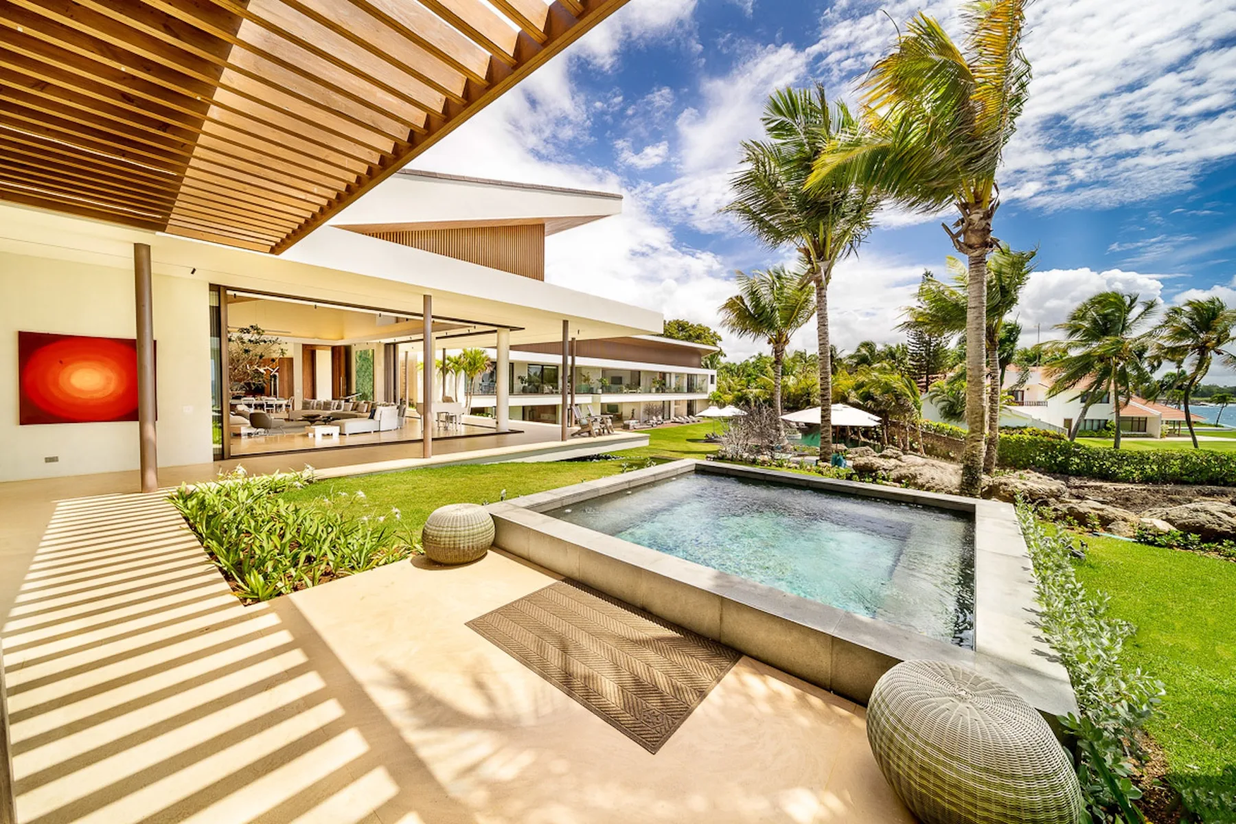 A modern outdoor pool beside a landscaped patio and palm trees.