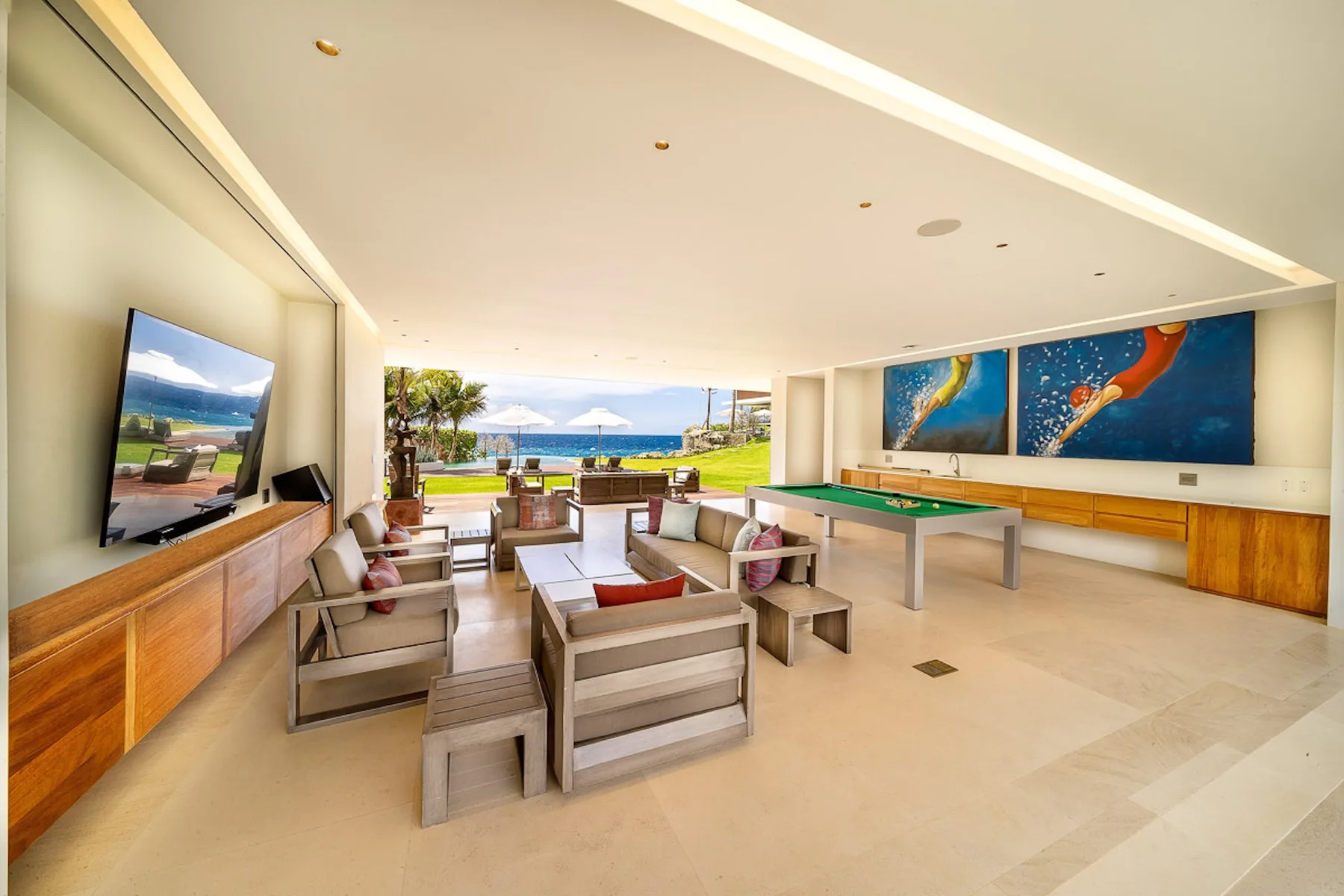 An open lounge with seating, a television, and a view toward the water.