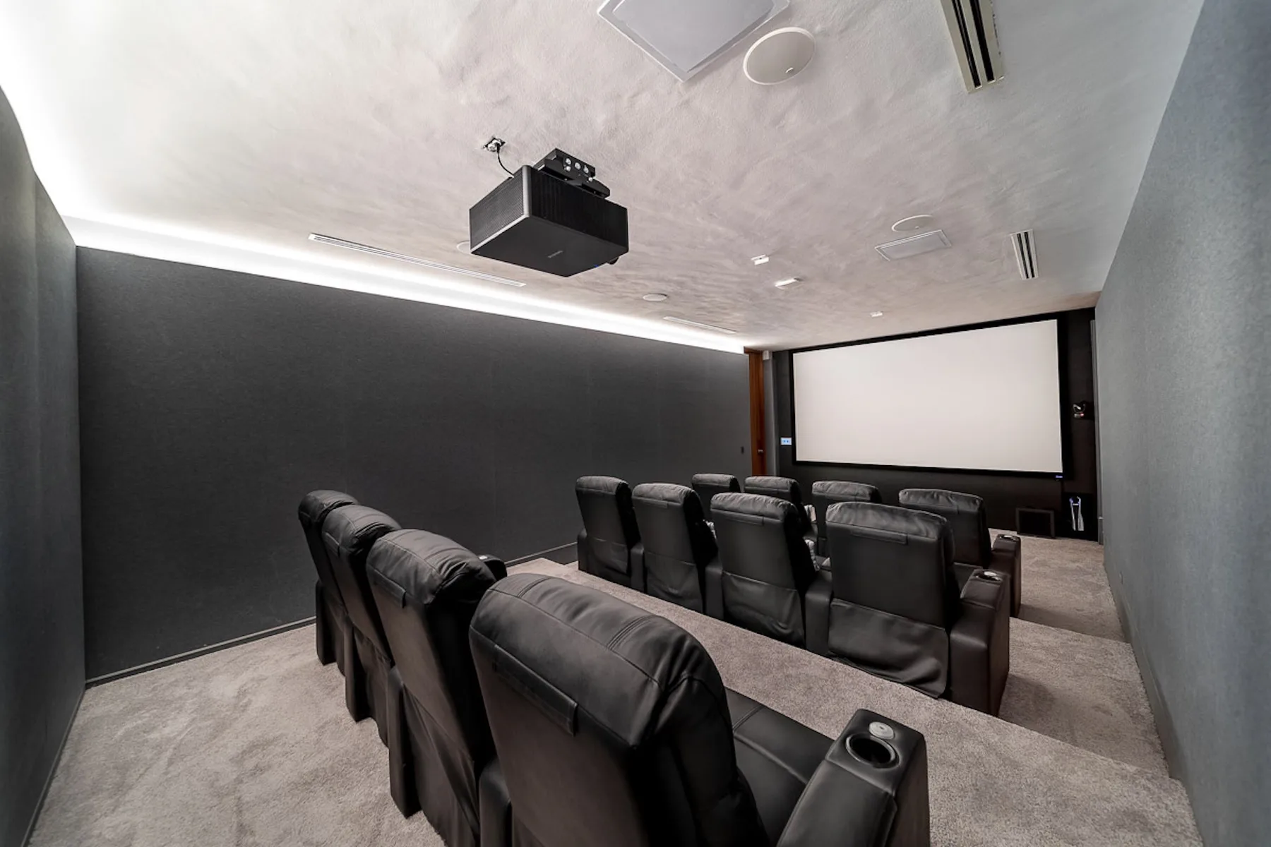 A home theater with rows of seating facing a large projection screen.