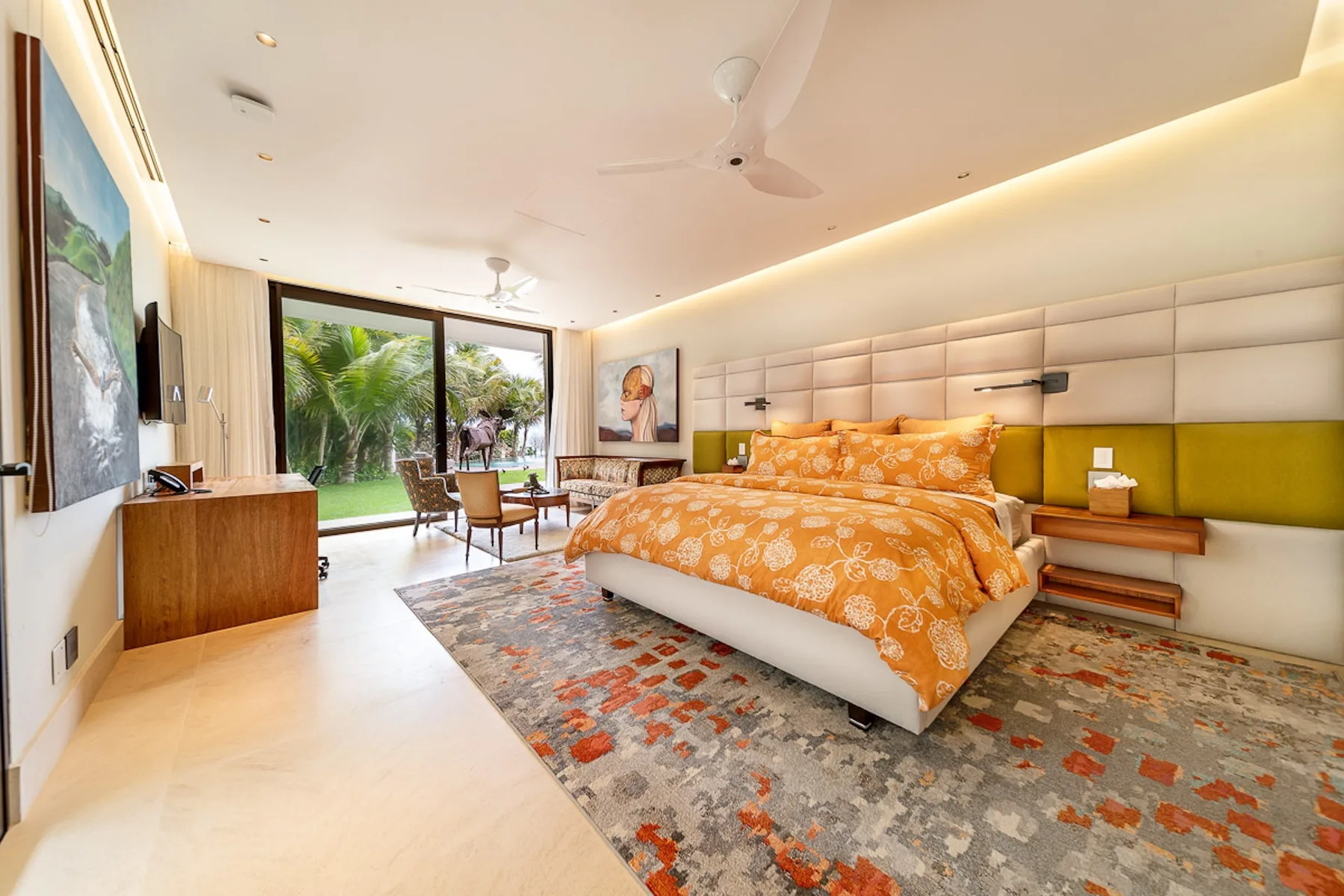 A bedroom with a large bed, bedside tables, and sliding glass doors opening to greenery.