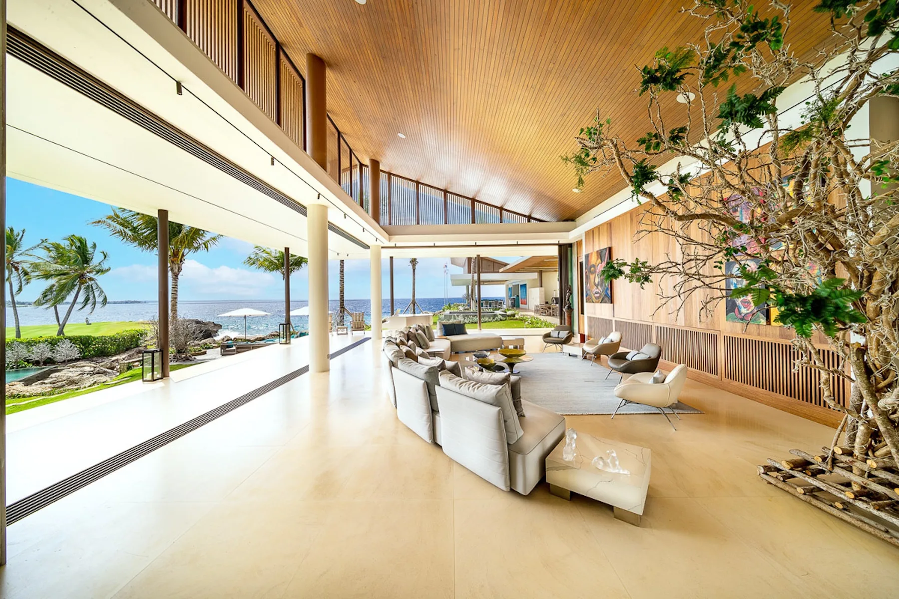 A spacious lounge with seating beside floor-to-ceiling windows overlooking the ocean.