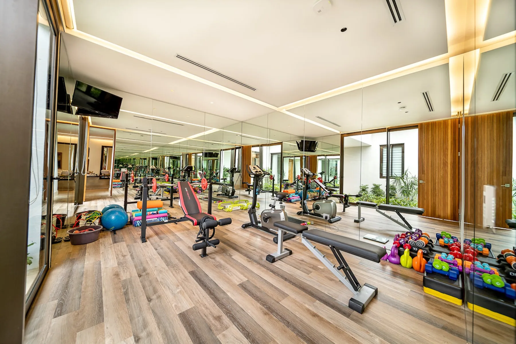 A gym with exercise machines, weights, and mirrored walls.