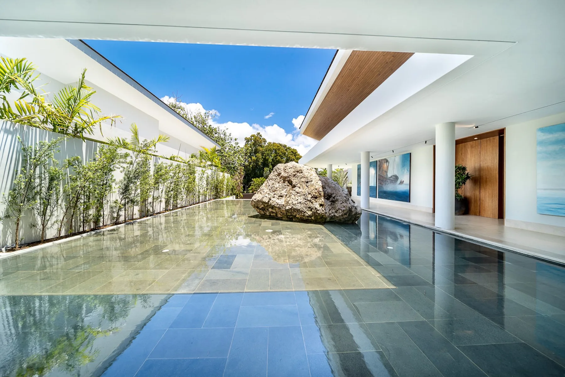 A modern courtyard with a shallow reflecting pool and a large central rock.