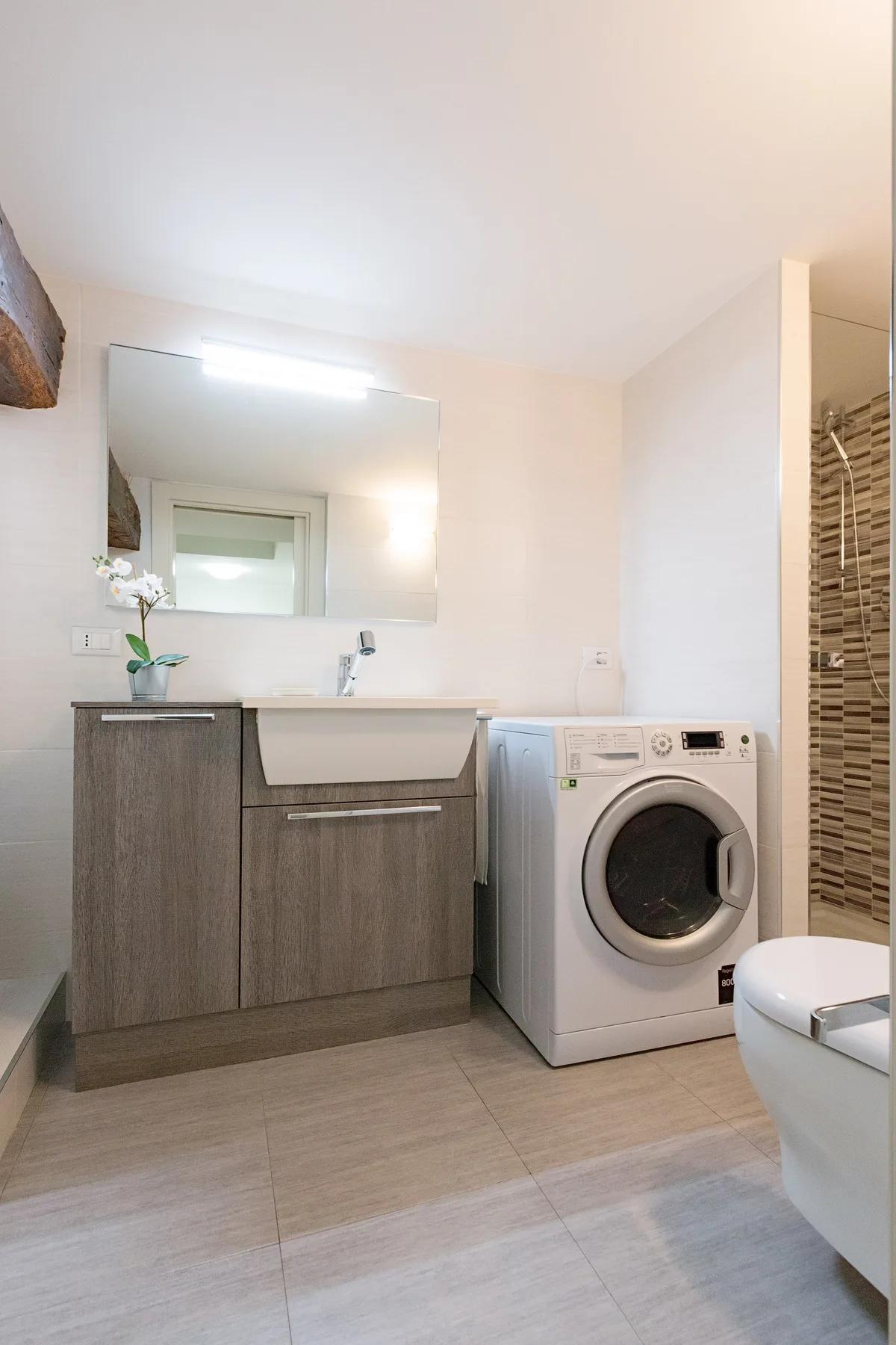 Un baño con mueble de lavabo, lavadora y zona de ducha.