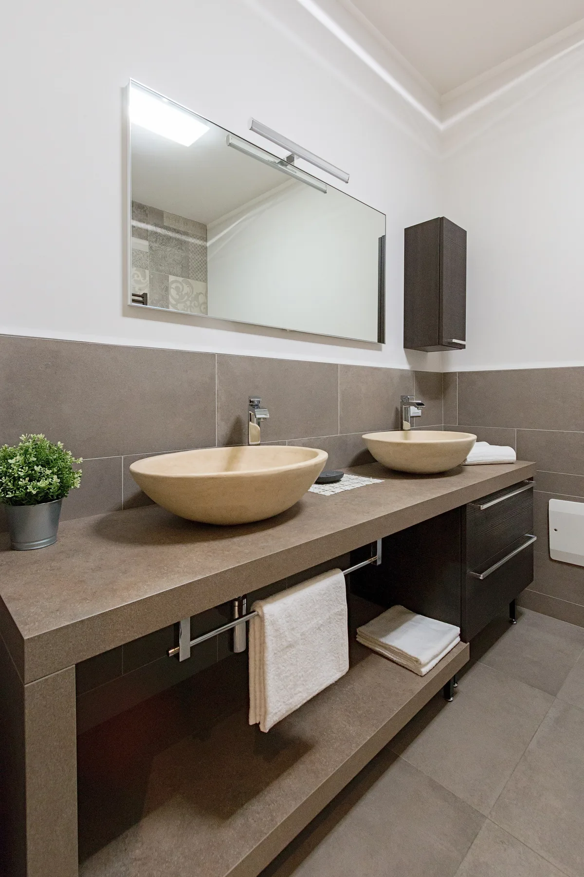 Un tocador de baño con dos lavabos sobre encimera bajo un espejo ancho.