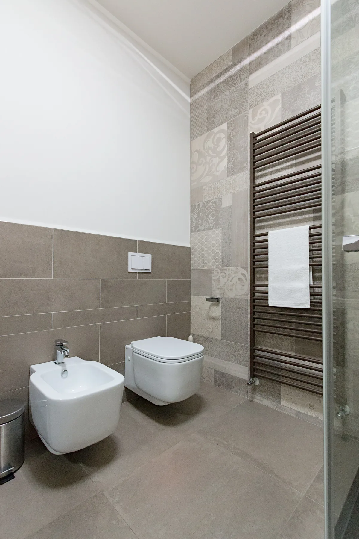 Un baño moderno con inodoro, bidé y radiador toallero.