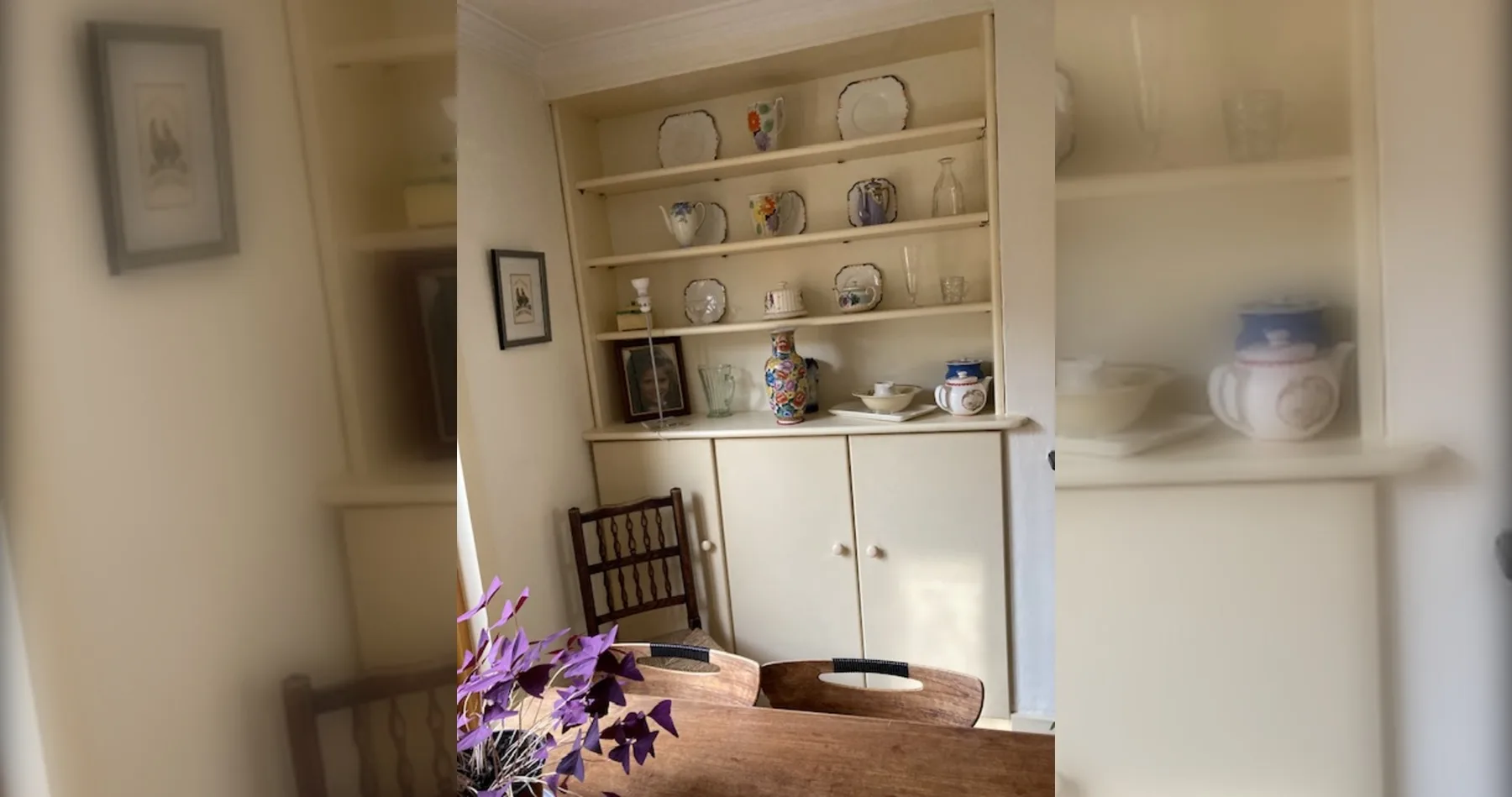 A dining area with a wooden table and a cabinet displaying dishes.