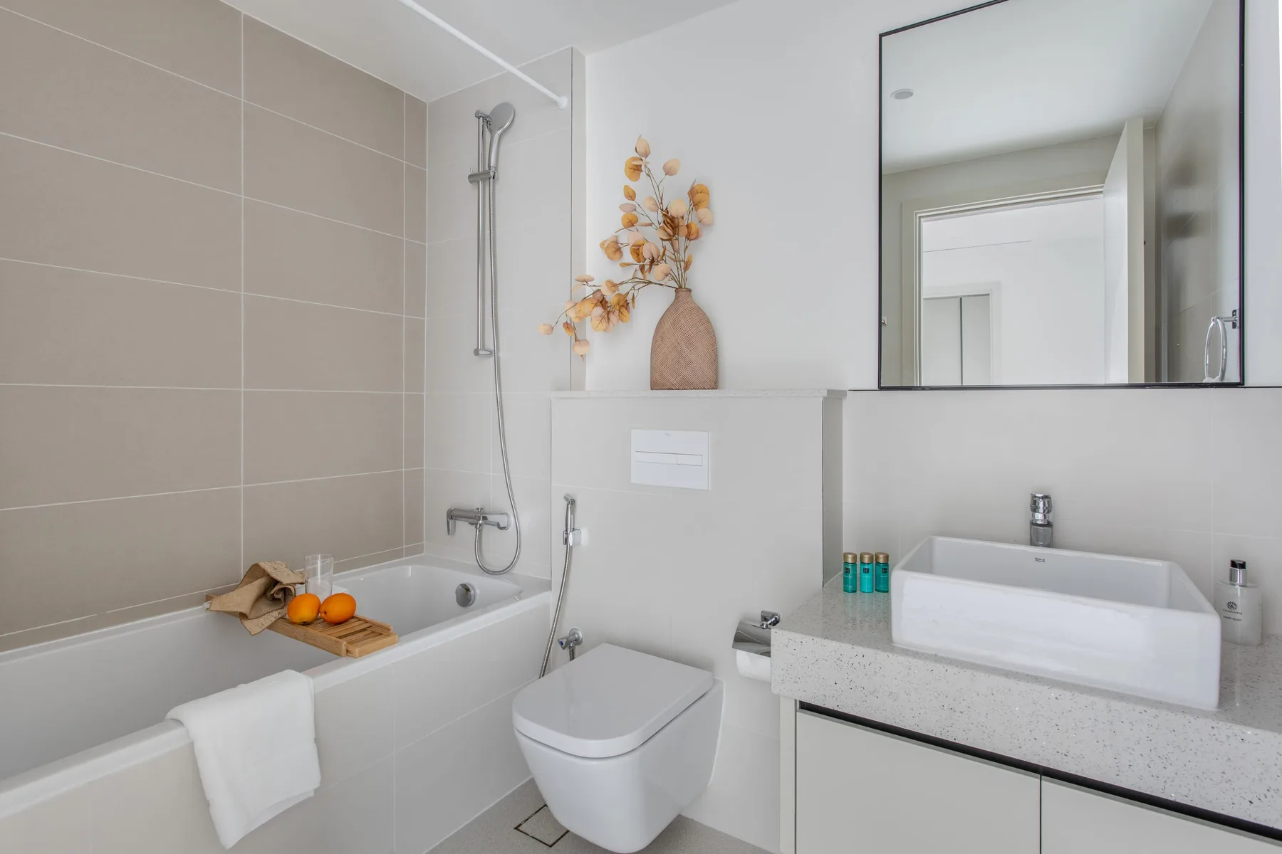 Un baño luminoso con bañera, inodoro y lavabo bajo un espejo grande.