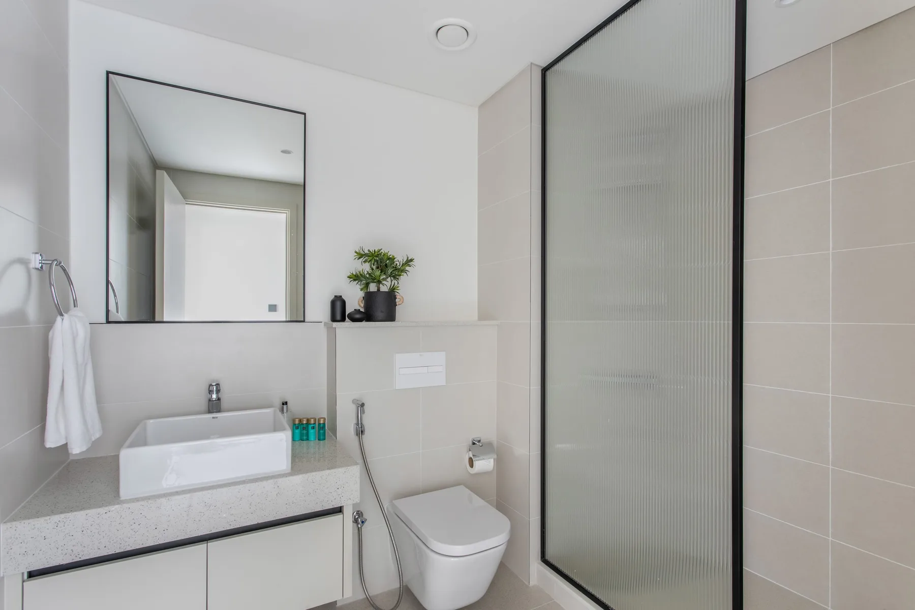 Un baño moderno con lavabo, inodoro y ducha de vidrio.