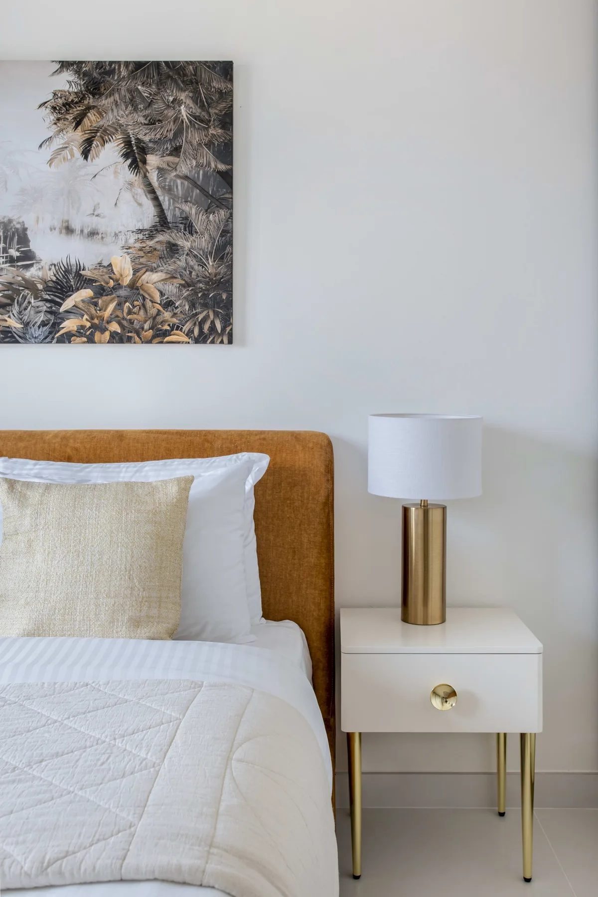 Un dormitorio con una cama bien tendida y una mesita de noche con una lámpara.