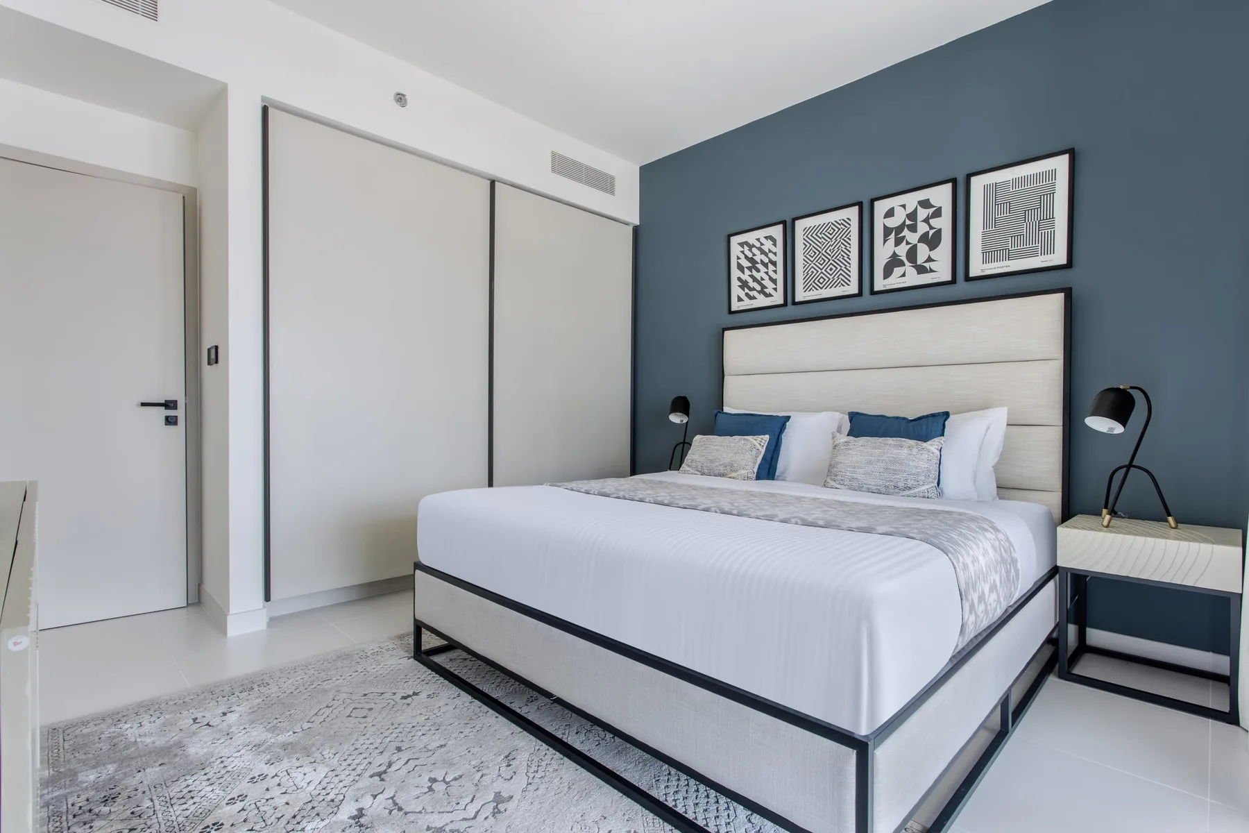 Un dormitorio con una cama bien hecha frente a una pared azul.