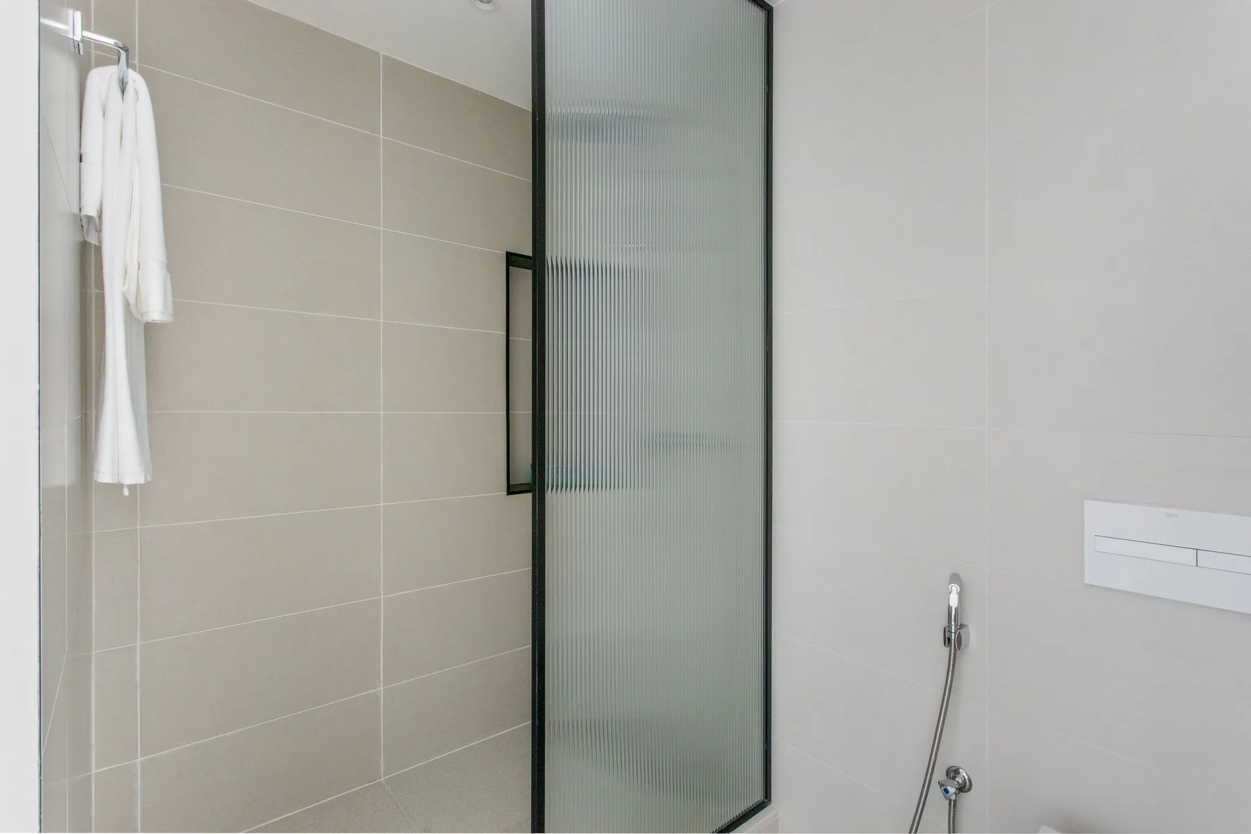 Un baño alicatado con una ducha y toallas colgadas en la pared.