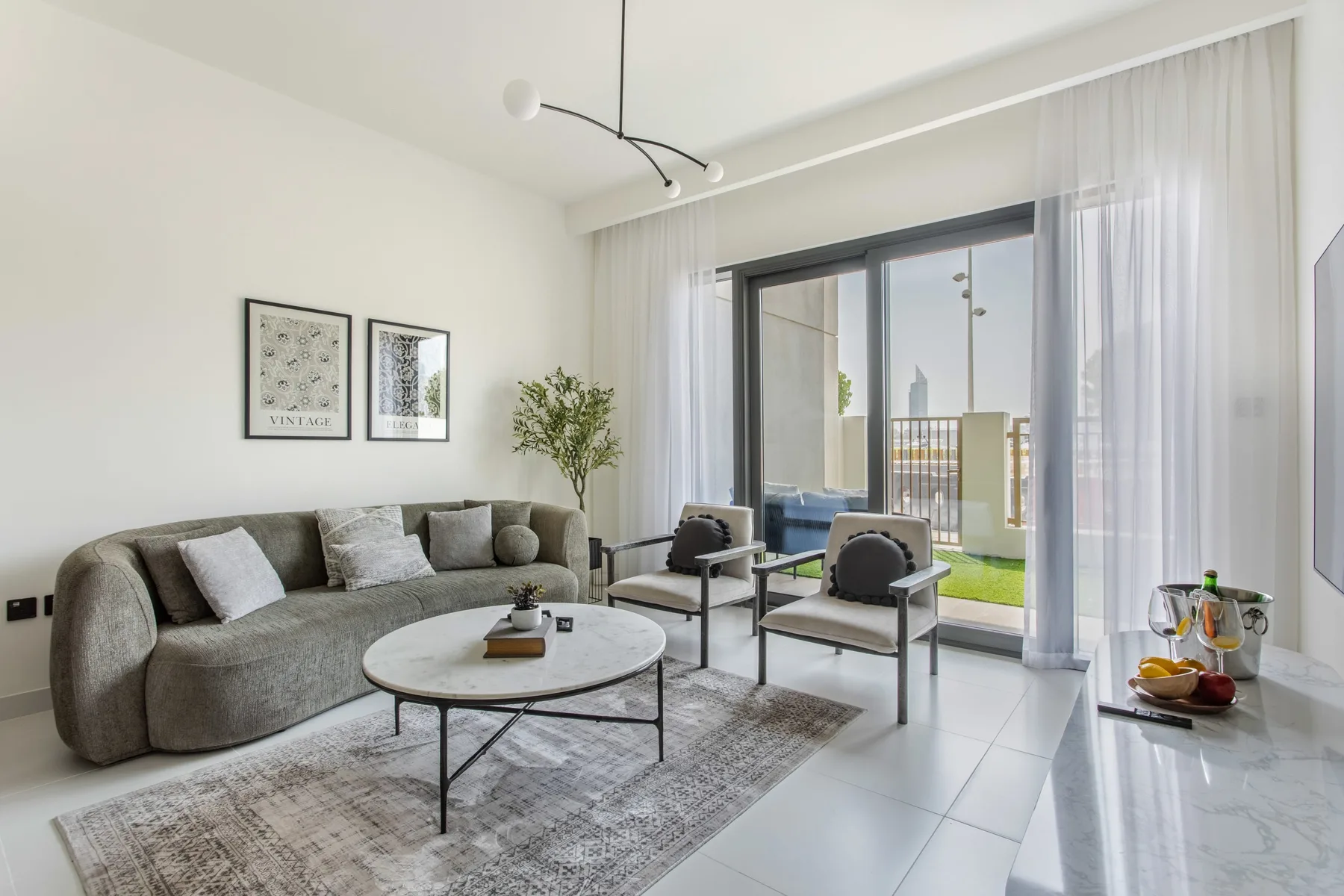 Una sala luminosa con asientos alrededor de una mesa de centro junto a puertas de vidrio altas.