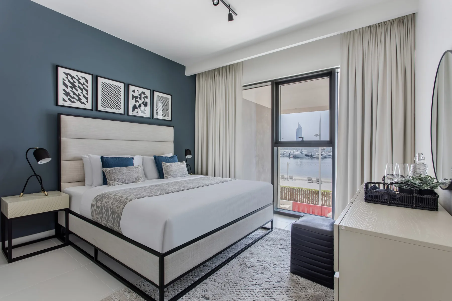 Un dormitorio moderno con una cama bien tendida y una ventana grande con vistas al agua.