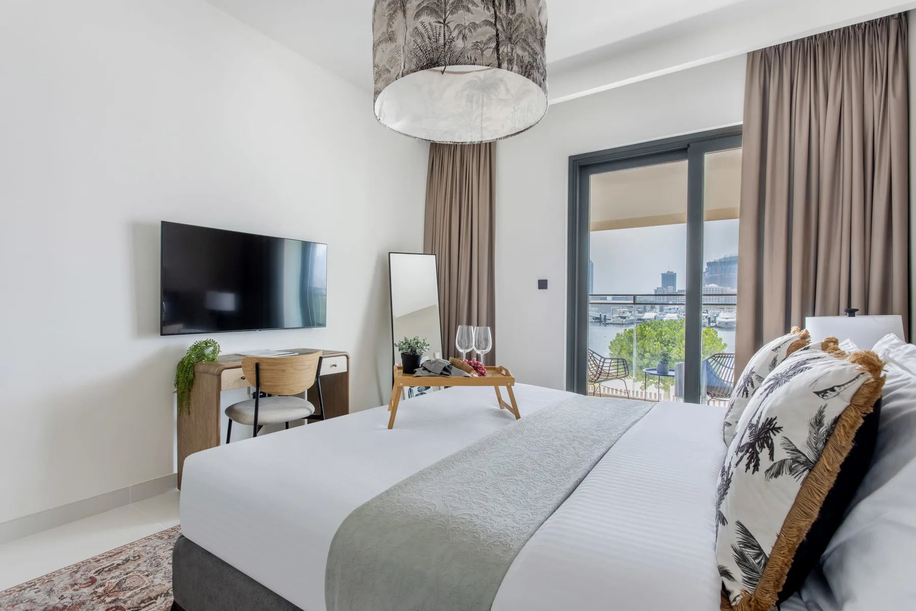 Un dormitorio luminoso con una cama bien hecha y puertas de vidrio que dan a un balcón.