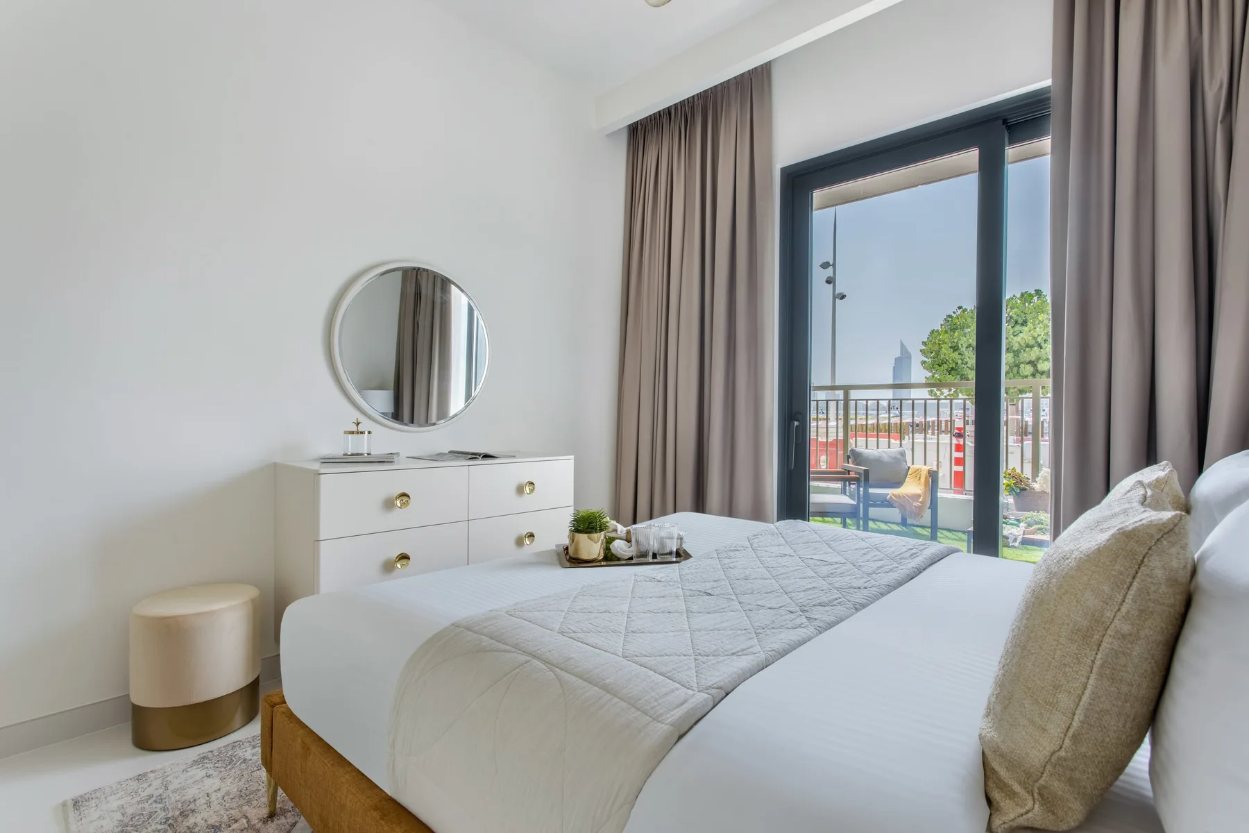 Un dormitorio luminoso con una cama bien hecha junto a una gran puerta de cristal.