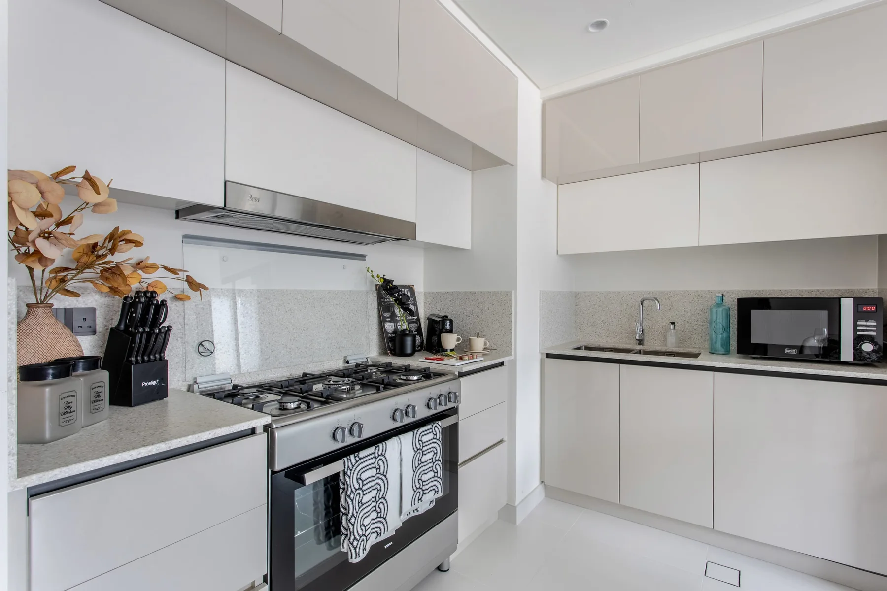 Una cocina moderna y luminosa con gabinetes blancos y una estufa de acero inoxidable.
